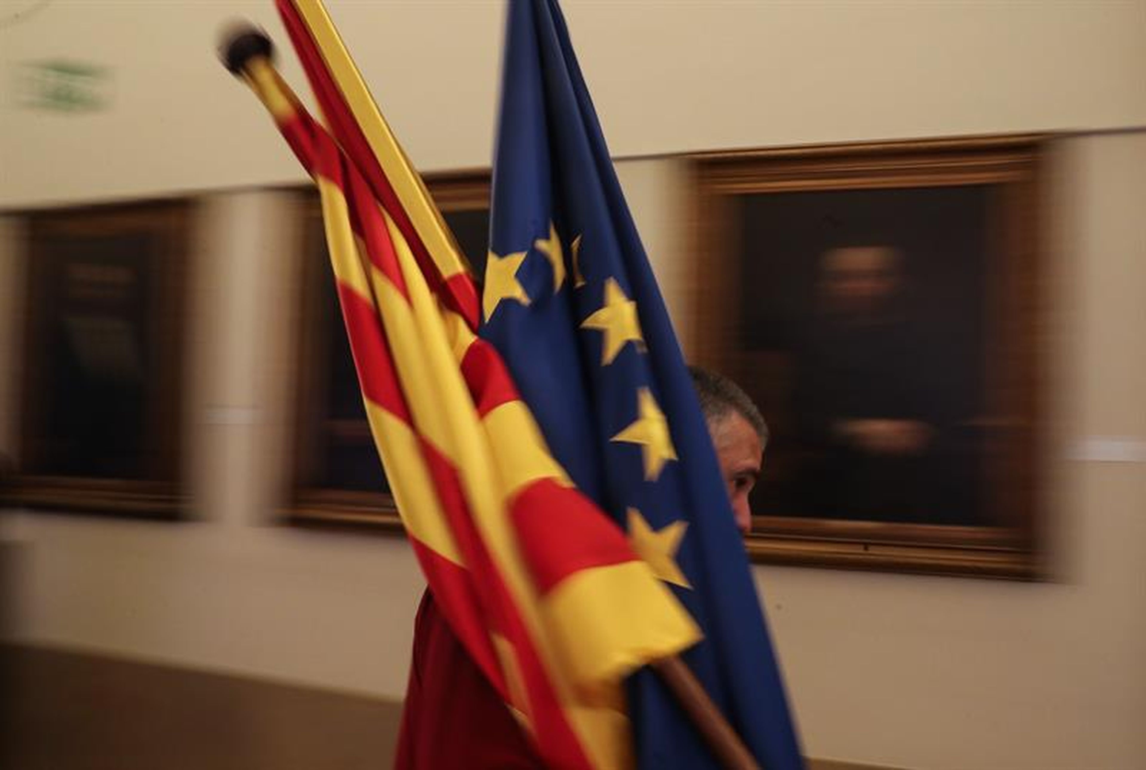 Un trabajador de la sede de la patronal catalana Fomento del Trabajo en Barcelona coloca unas banderas.