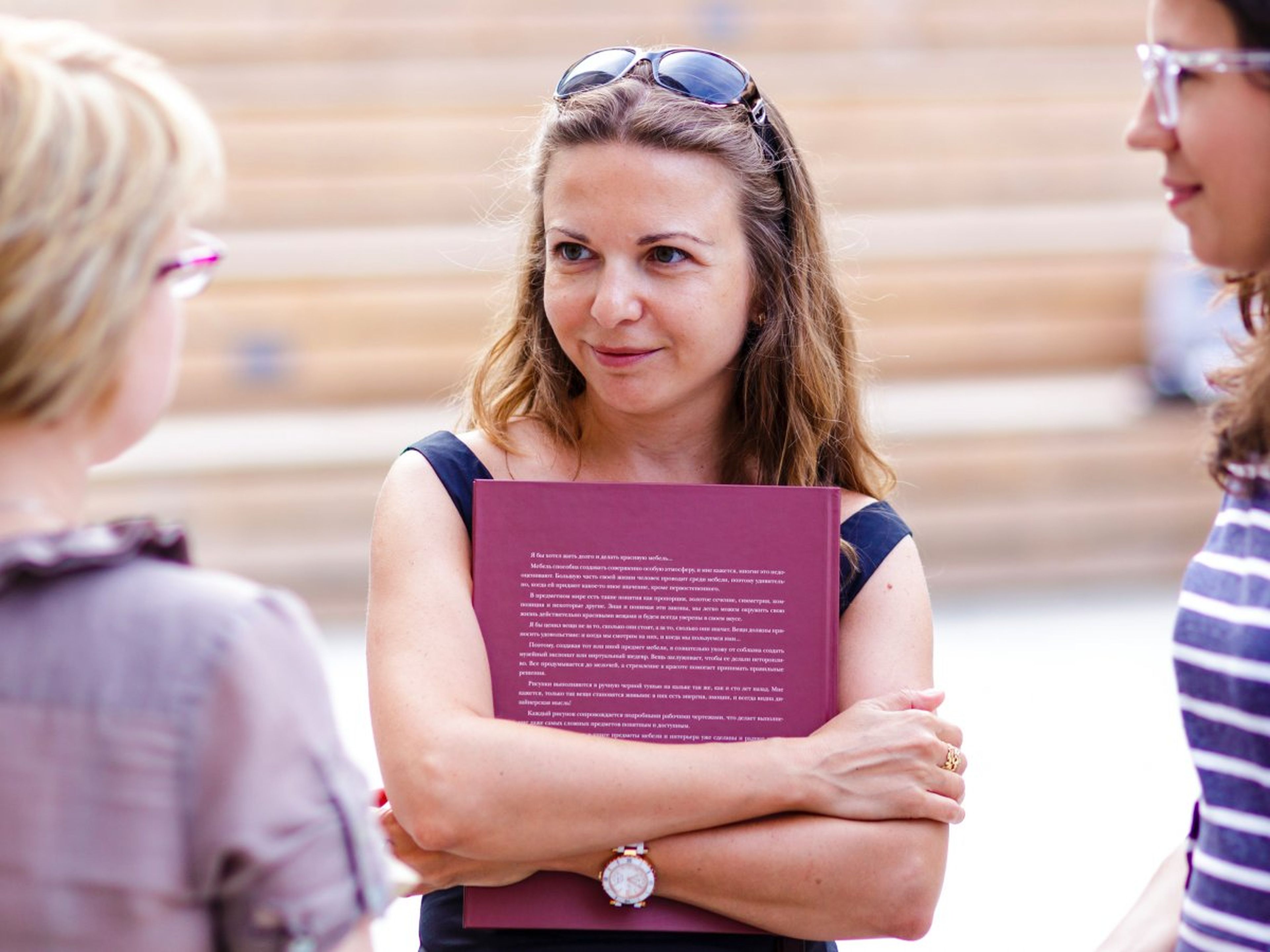 Una mujer sujeta un libro mientras mantiene una conversación con otras dos