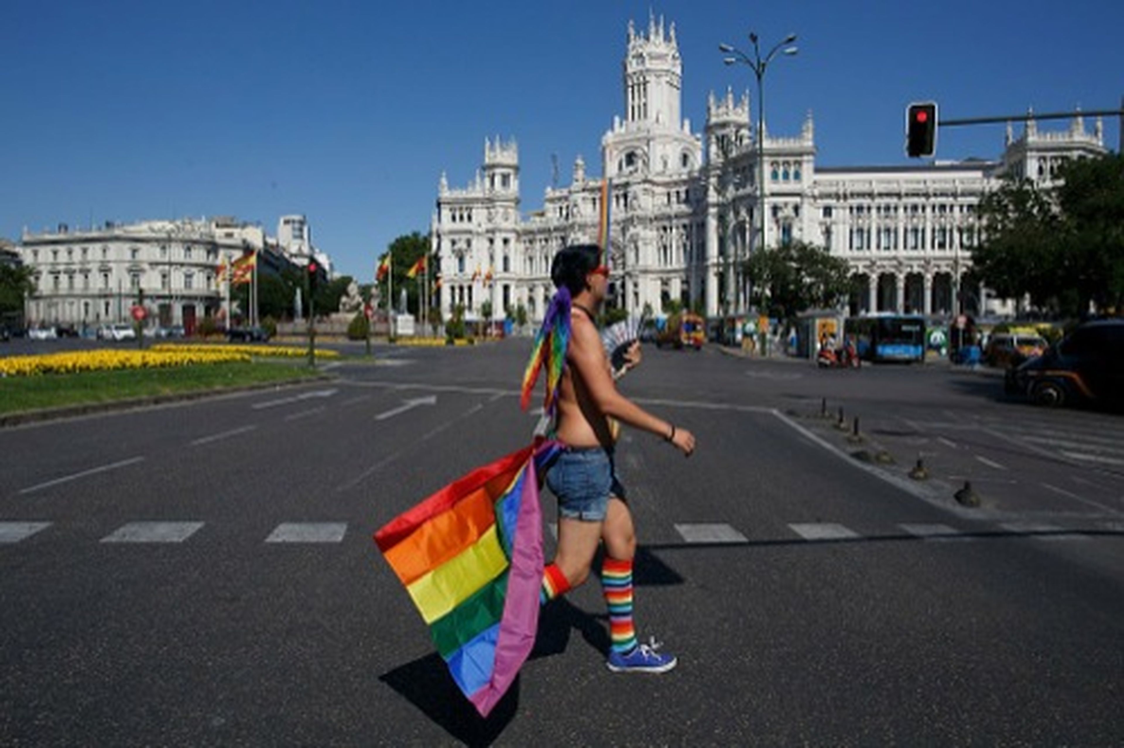 Participante en el Orgullo Gay de Madrid con una bandera arcoiris por las calles aledañas a la Plaza de Cibeles antes del desfile del Orgullo, el 29 de junio de 2016, en Madrid (España).