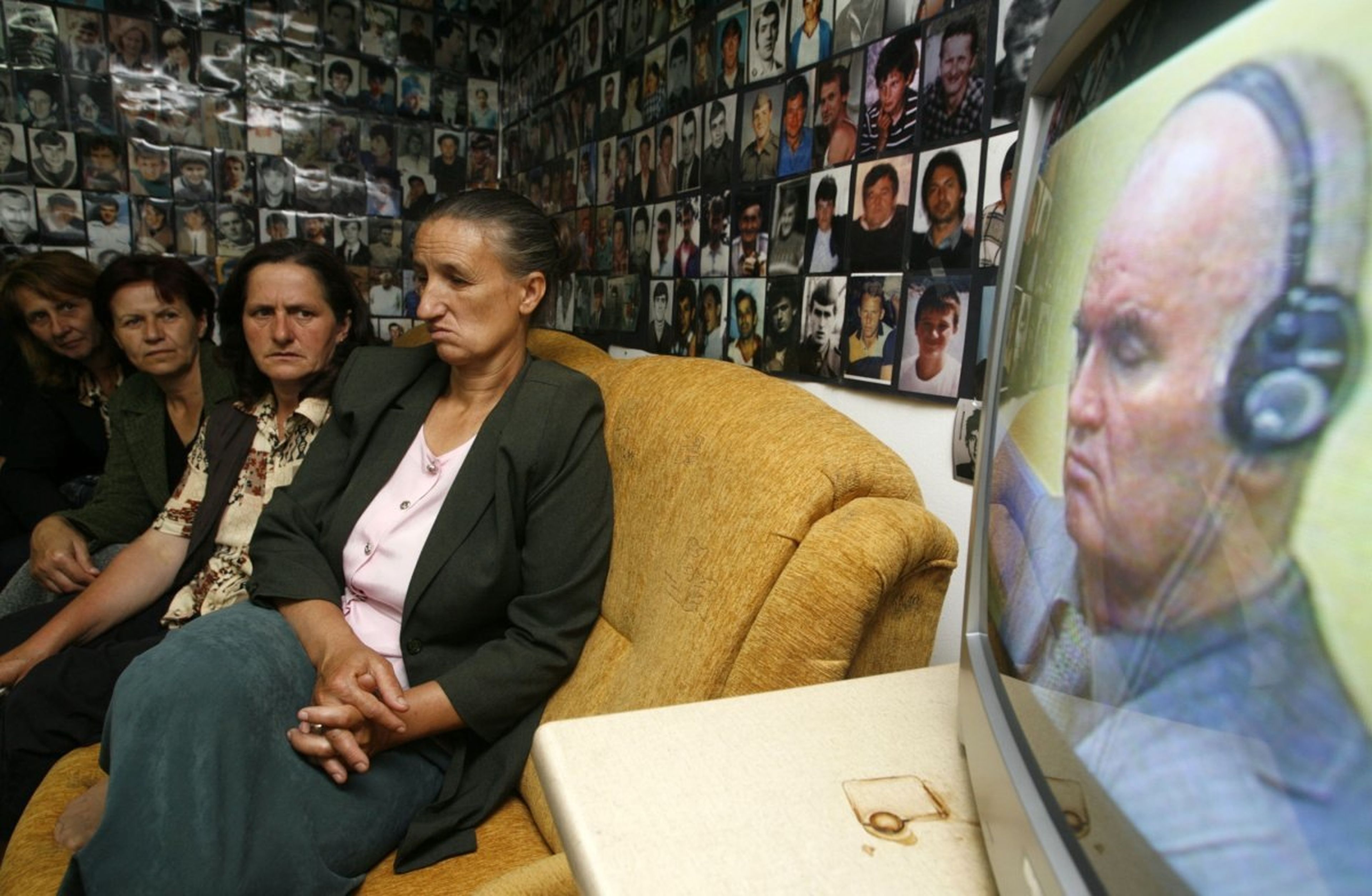 Mujeres musulmanas bosnias de Srebrenica, rodeadas de fotografías de víctimas del genocidio ocurrido en la ciudad durante la guerra bosnia de 1992 a 1995, miran la retransmisión televisiva del juicio contra Mladic en Tuzla, el 3 de junio de 2011.