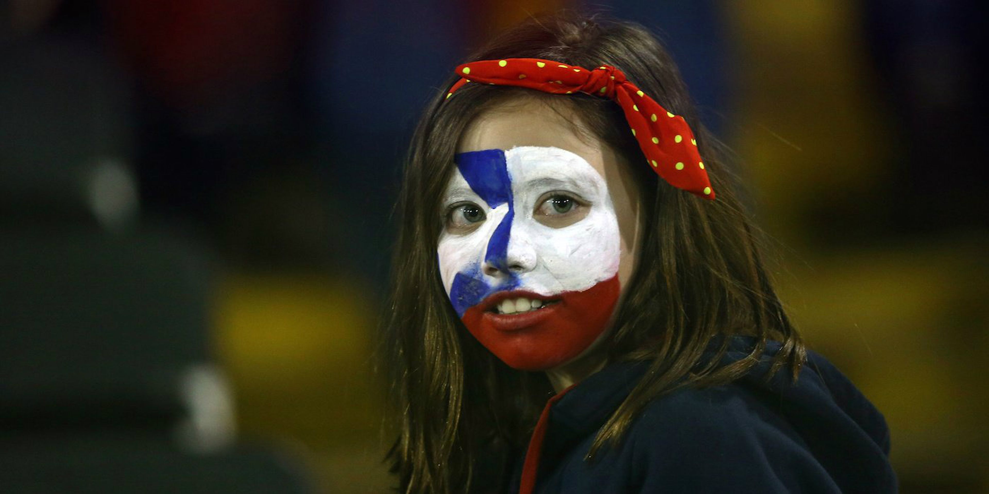 Una niña con la bandera de Chile pintada en su cara durante un partido de la selección nacional de fútbol contra Colombia en el Estadio Monumental de Santiago de Chile el 6 de septiembre de 2016.