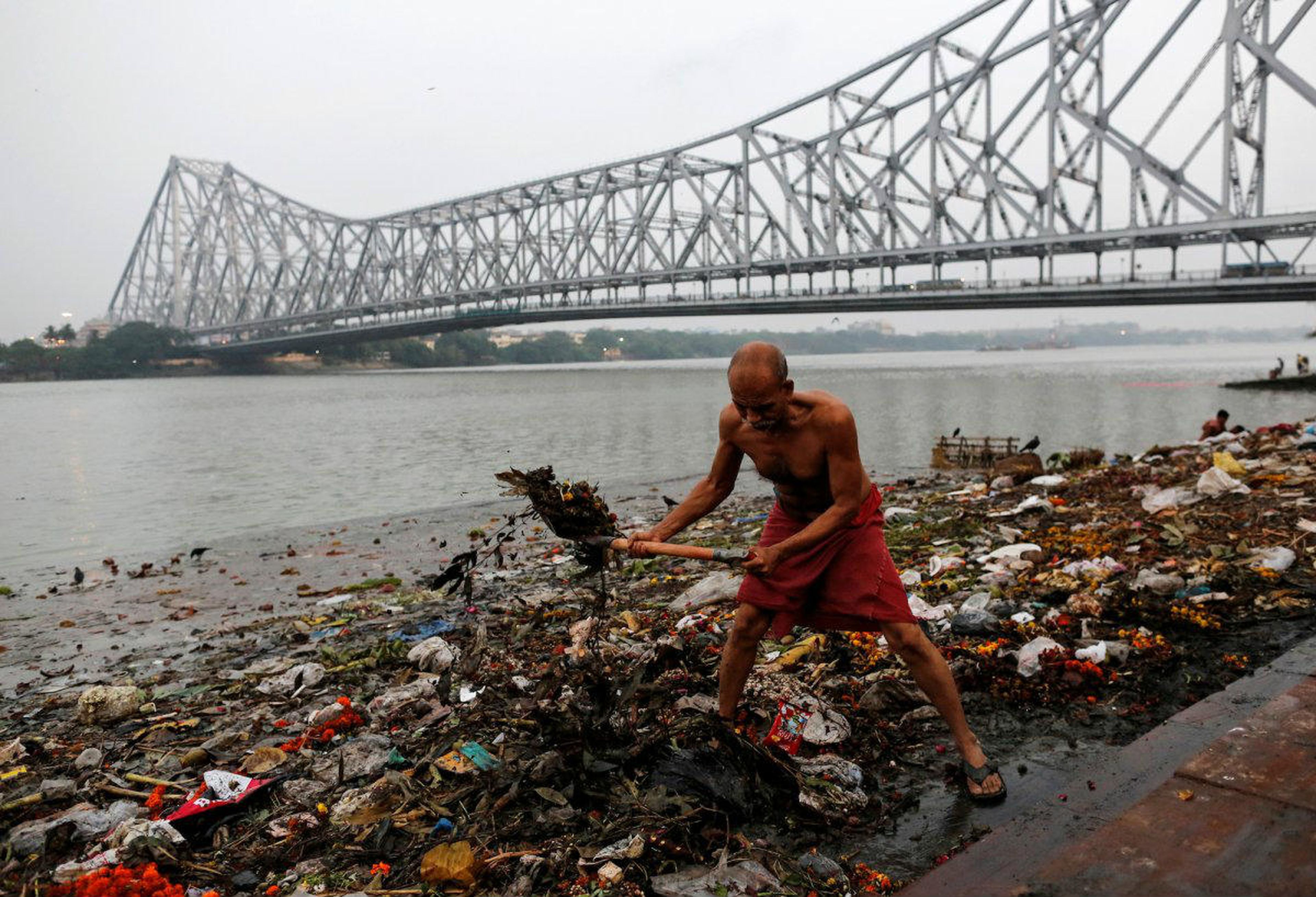 Un hombre recoge basura a lo largo de las orillas del río Ganges en Calcuta (India) el 9 de abril de 2017.