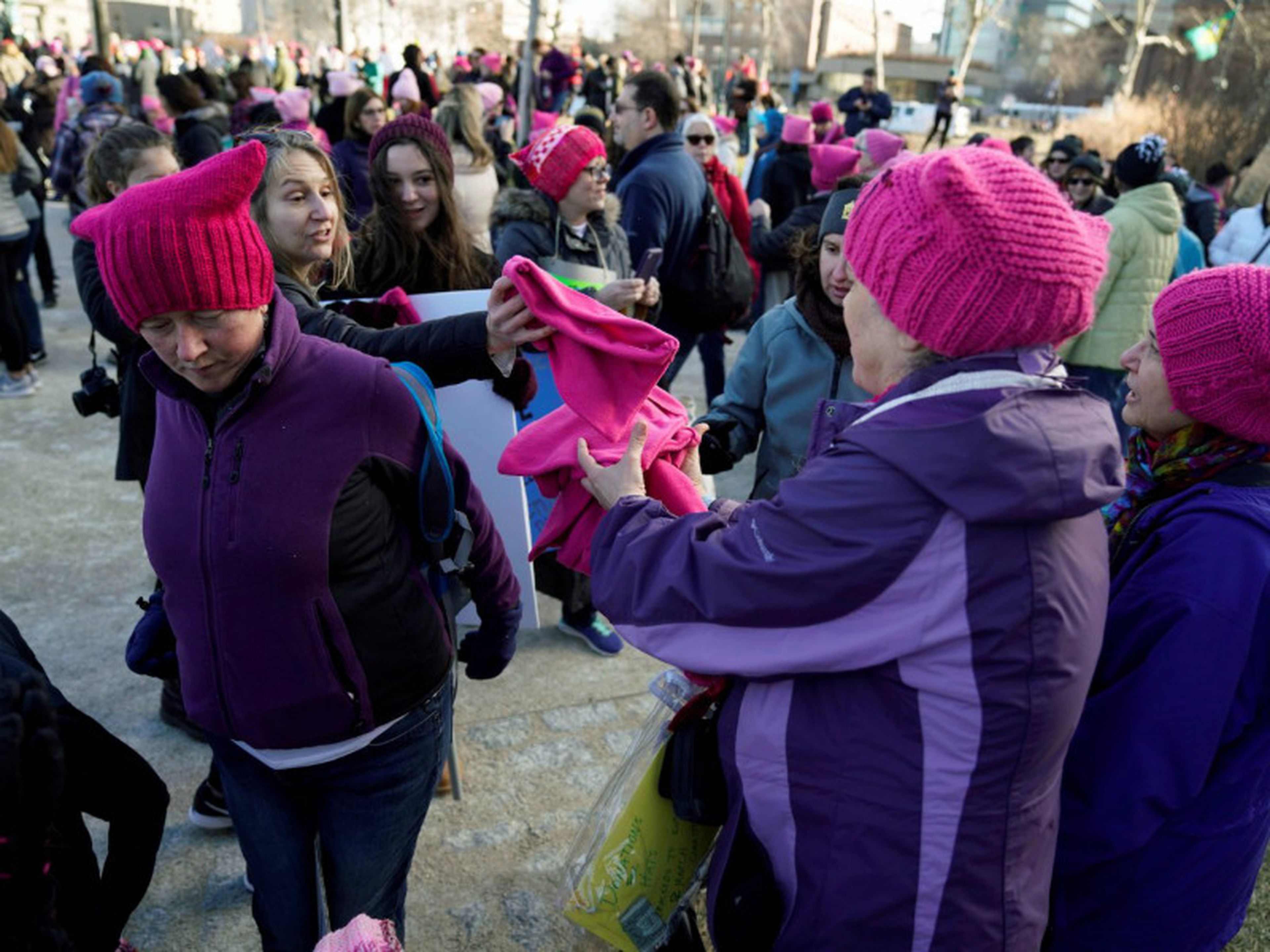 Unas mujeres reparten gorros rosas al inicio de la marcha.