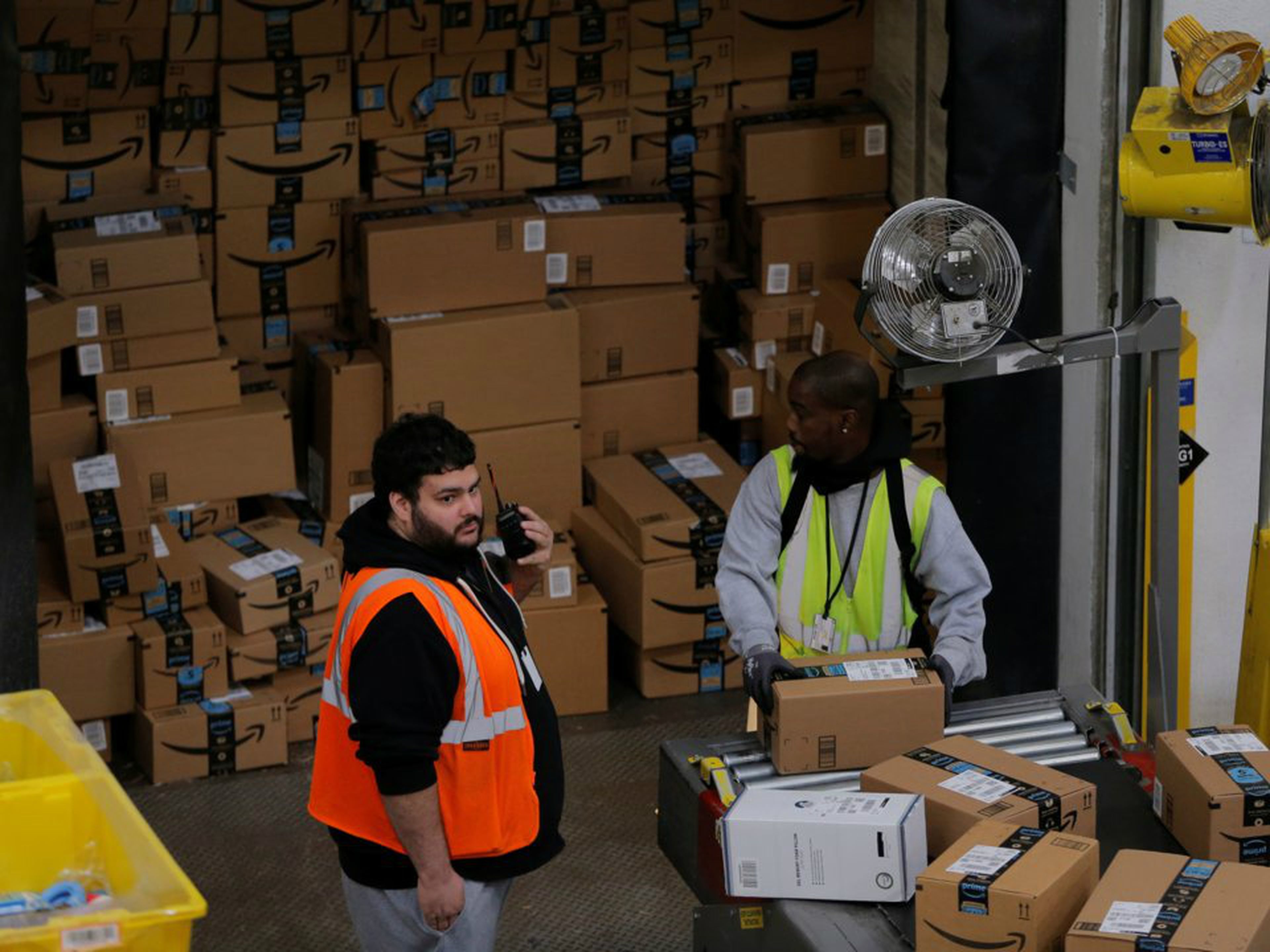 Dos operarios etiquetan y ordenan paquetes de Amazon.