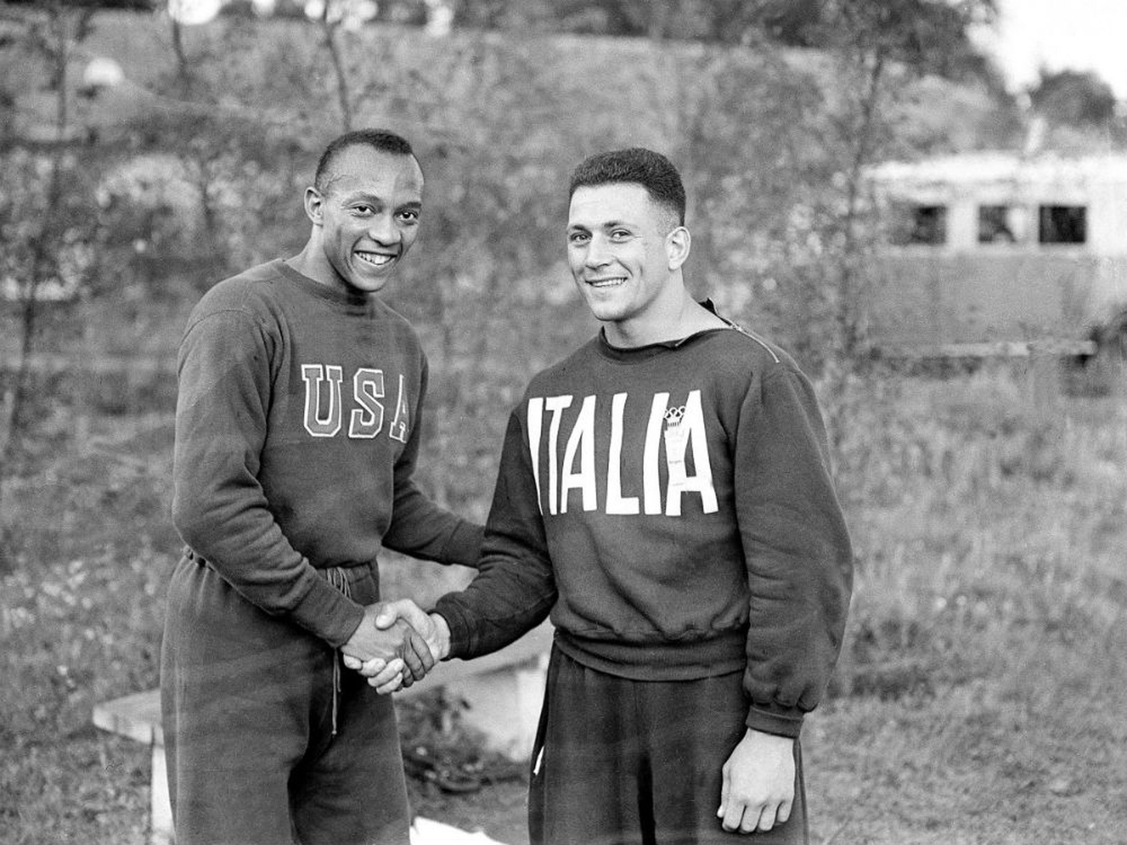 El atleta estadounidense Jesse Owens (izqd.) da la mano a su rival italiano Ercola Gallegati en la Villa Olímpica de Berlín 1936.