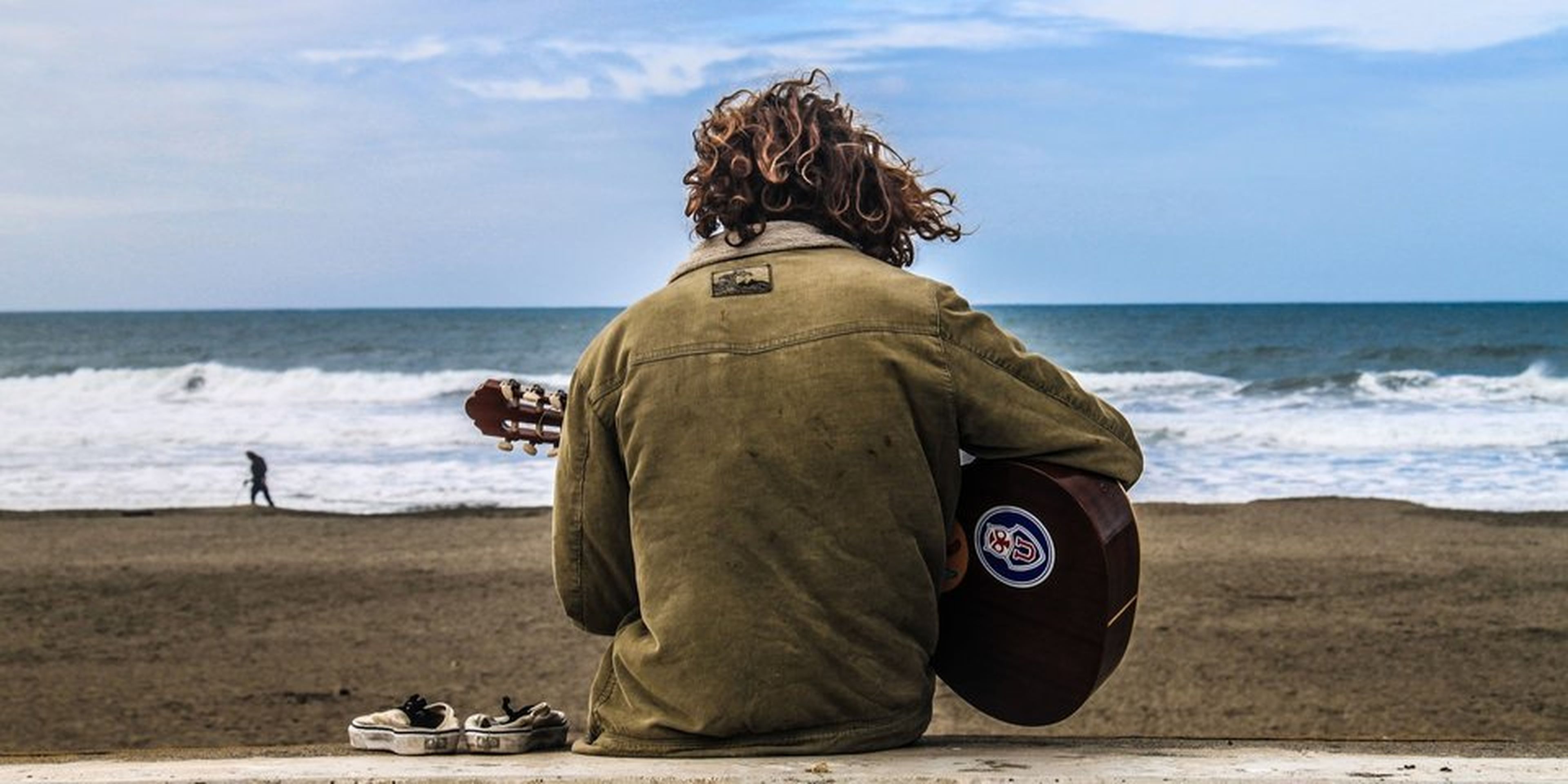 Hombre toca la guitarra en la playa