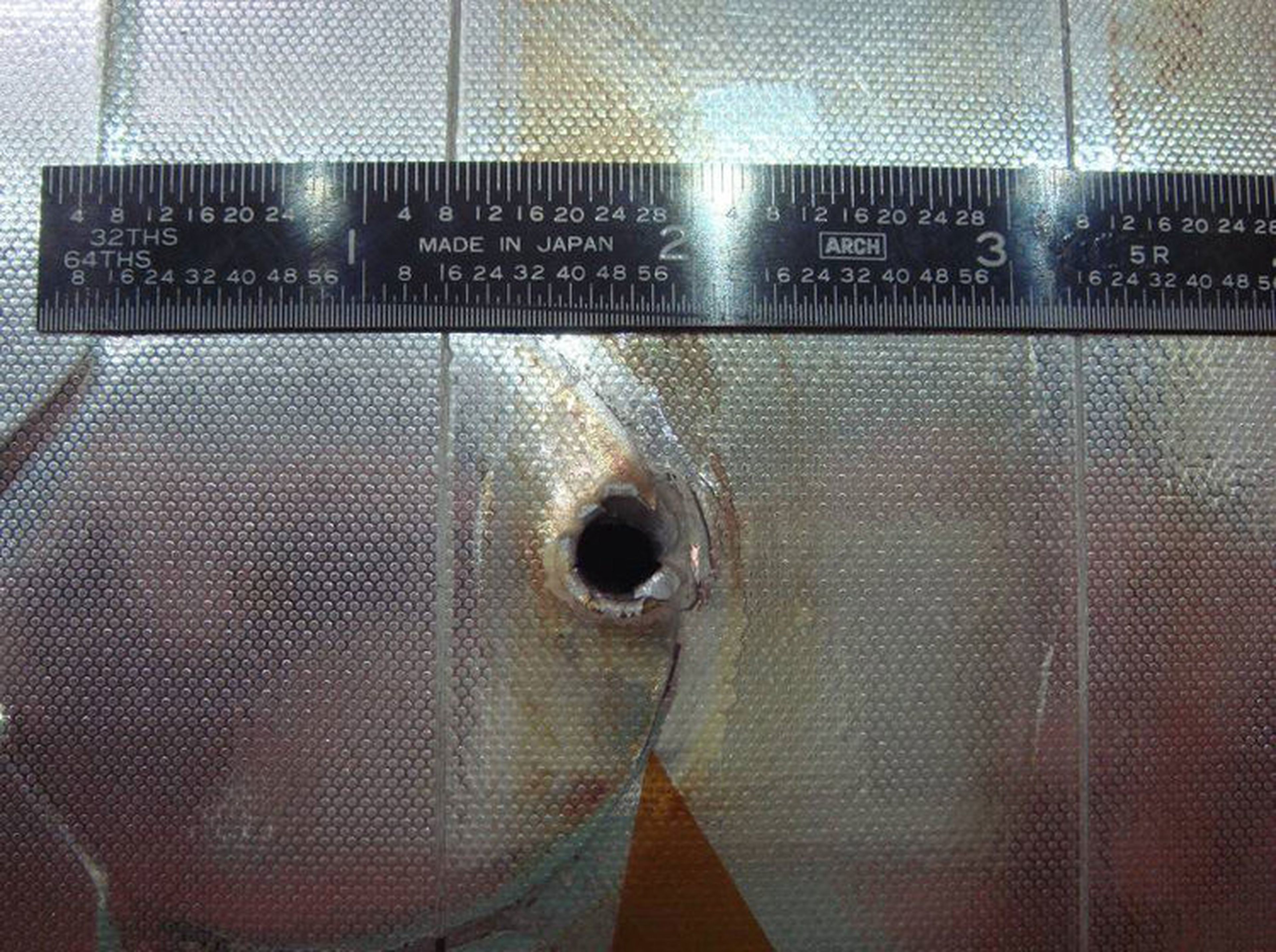 Un golpe de un fragmento espacial al radiador del transbordador espacial Endeavour que se encontró después de una de sus misiones. El orificio de entrada mide aproximadamente 0.63 cm de ancho, y el orificio de salida es dos veces más grande.