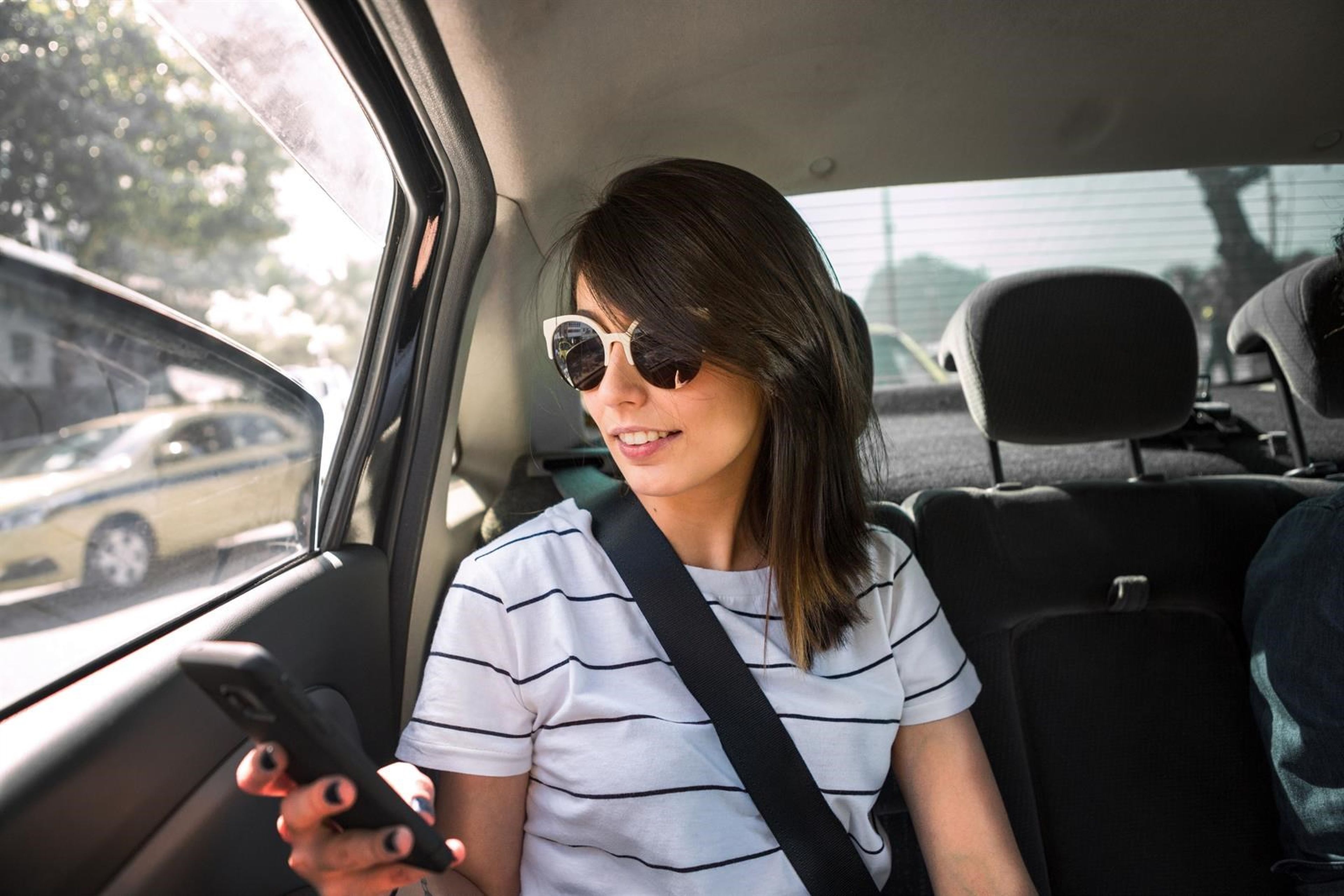 Una joven utiliza un móvil dentro de un coche.