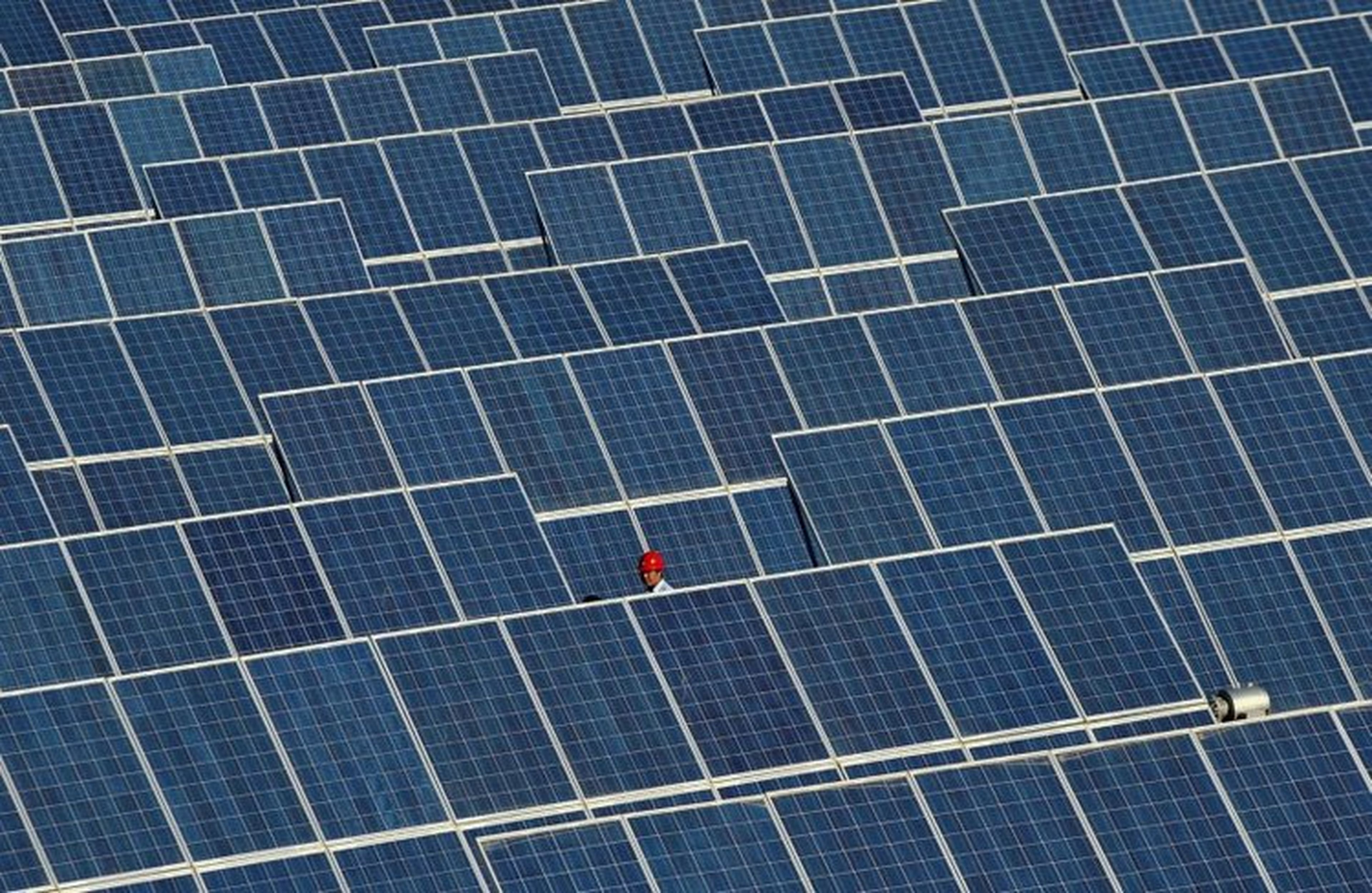 Un empleado camina entre los paneles de una central de energía solar en China.