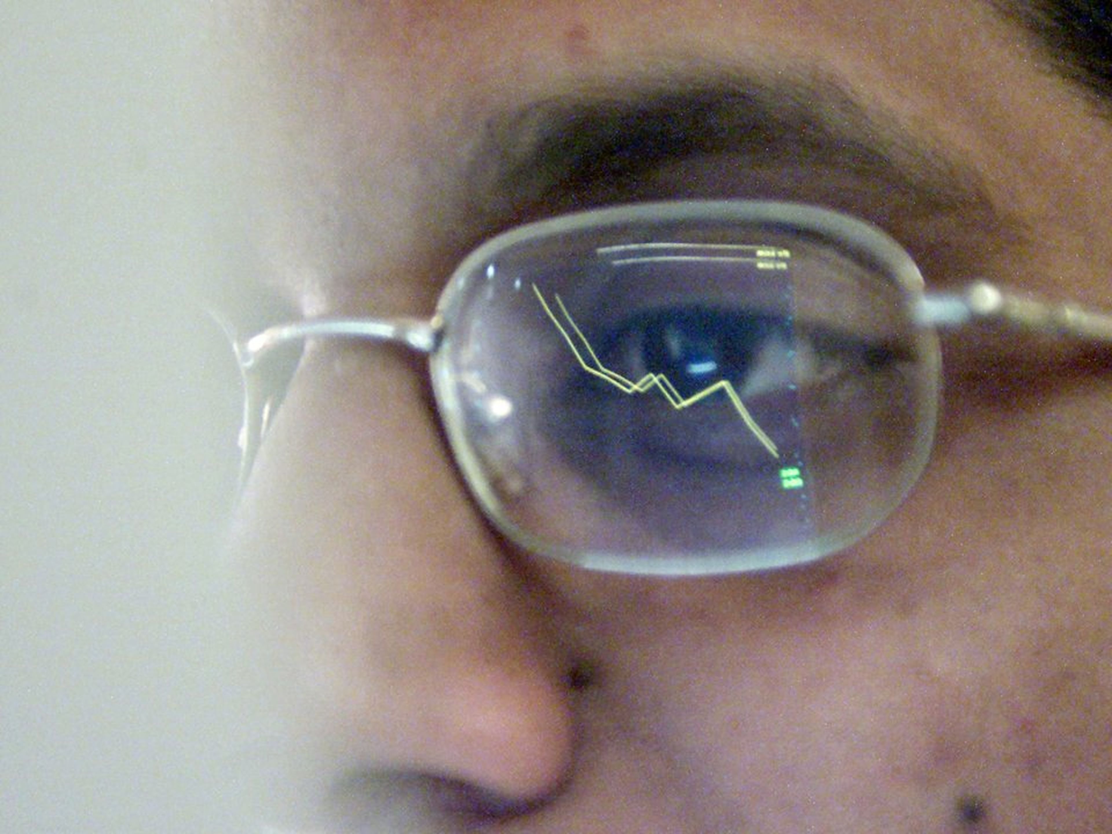 Primer plano de hombre con gafas reflejando curva de datos