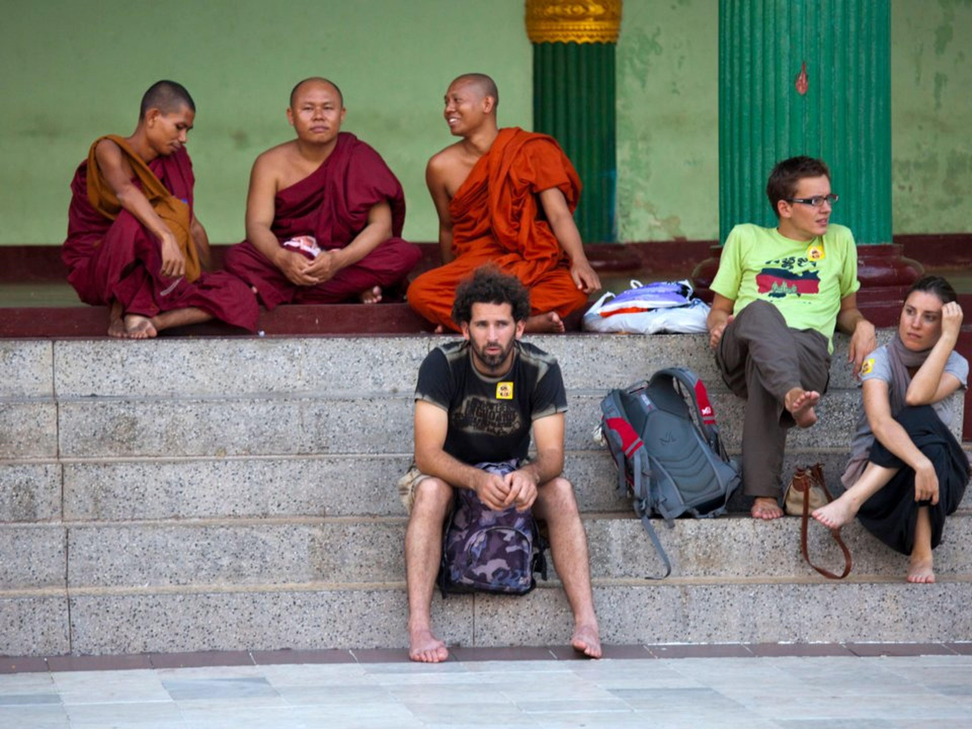 Turistas descansan al lado de monjes