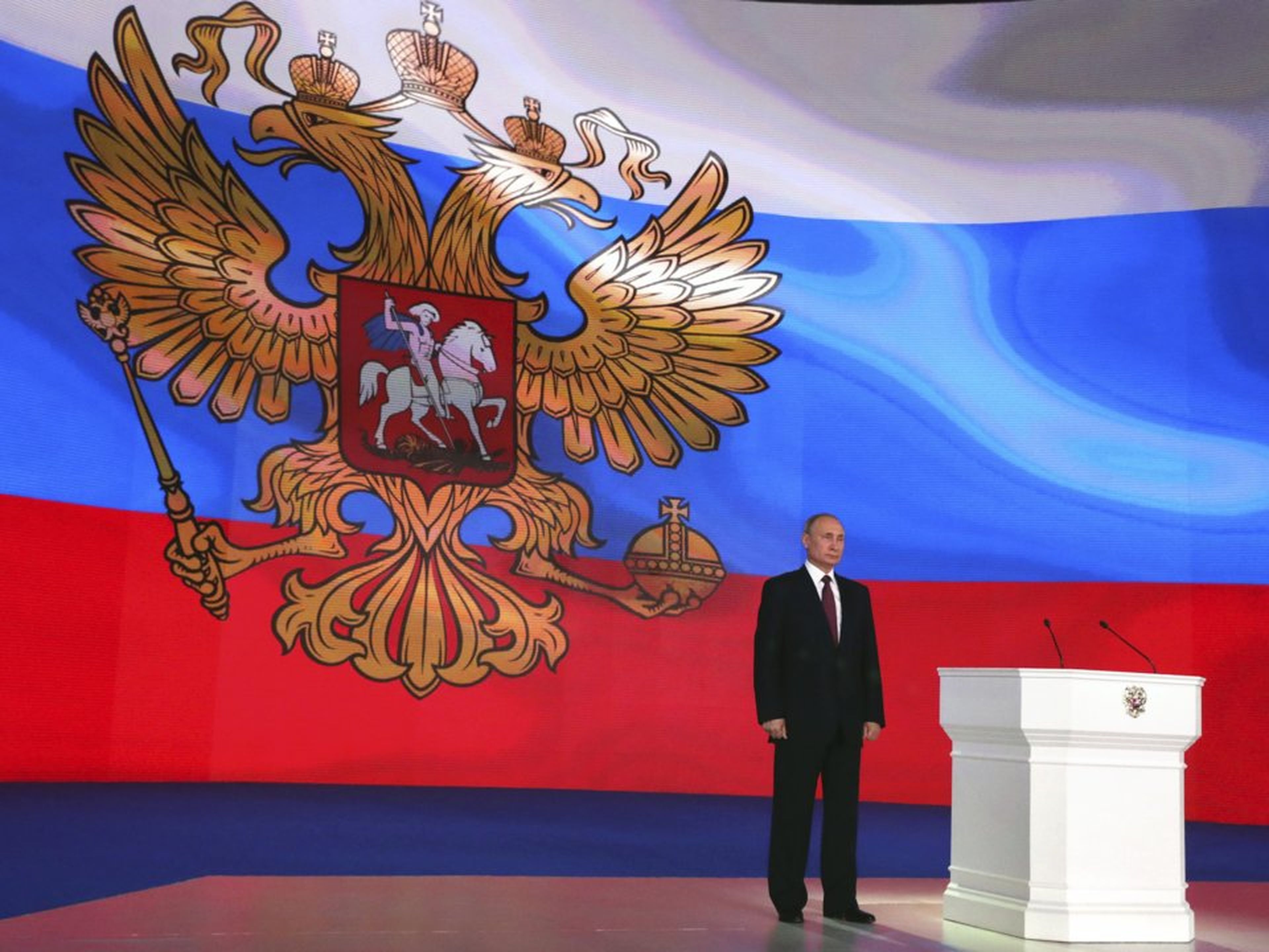 Vladimir Putin de pie delante de una bandera nacional