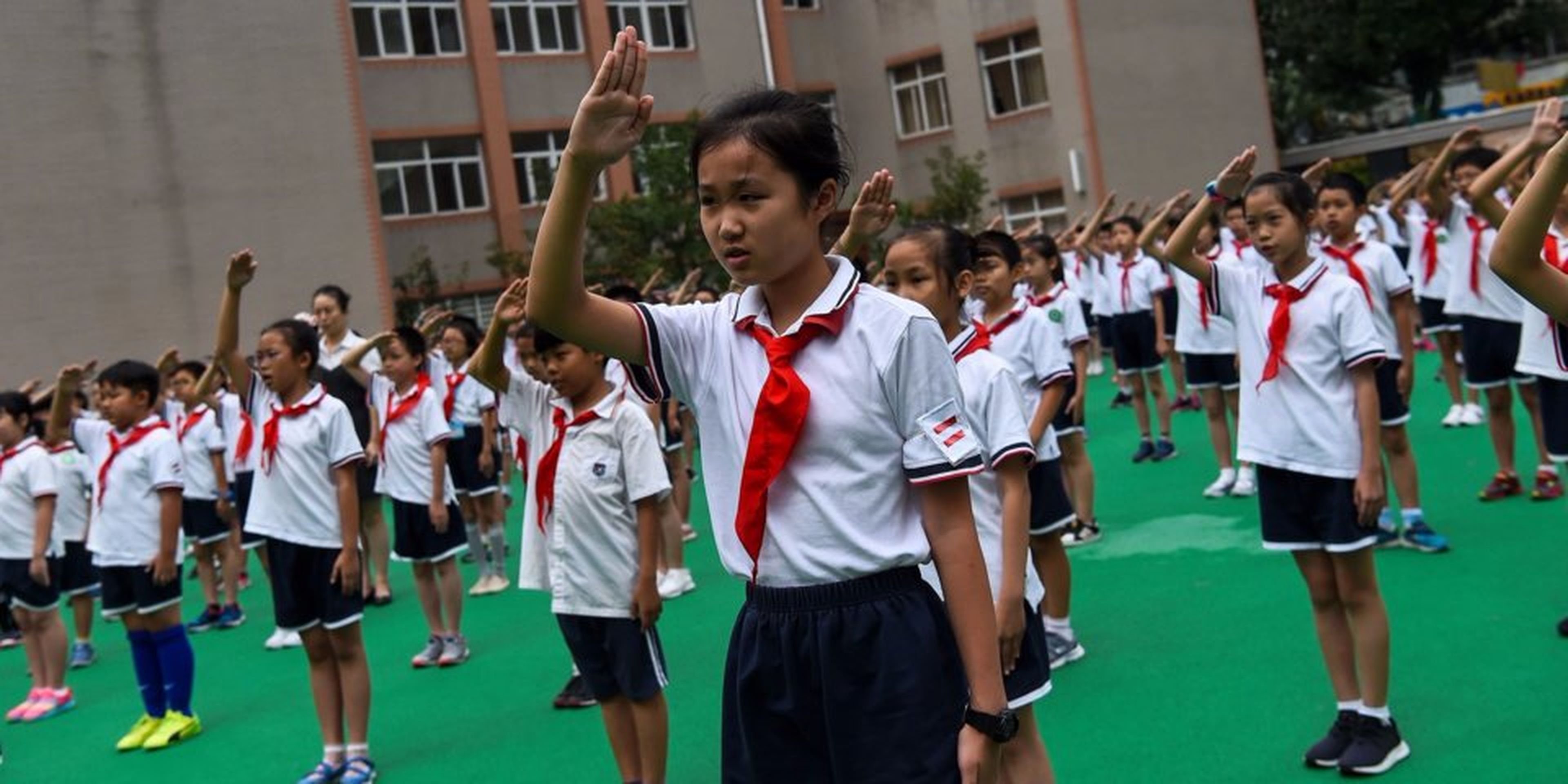 Unos estudiantes cantan el himno nacional en el patio de recreo durante la jura de bandera en una escuela de Shanghai el 27 de septiembre de 2017.