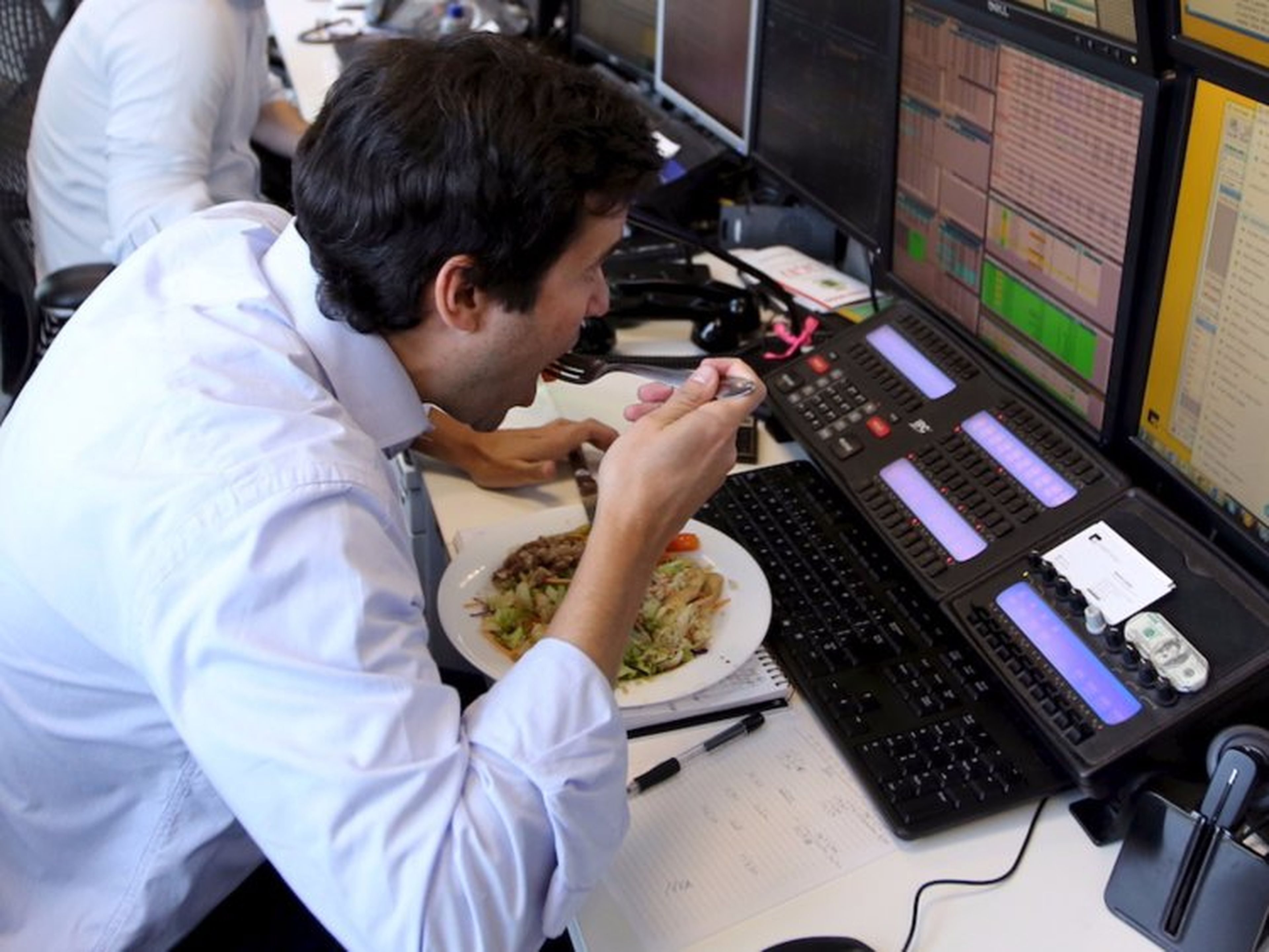 Un hombre comiendo delante de su ordenador