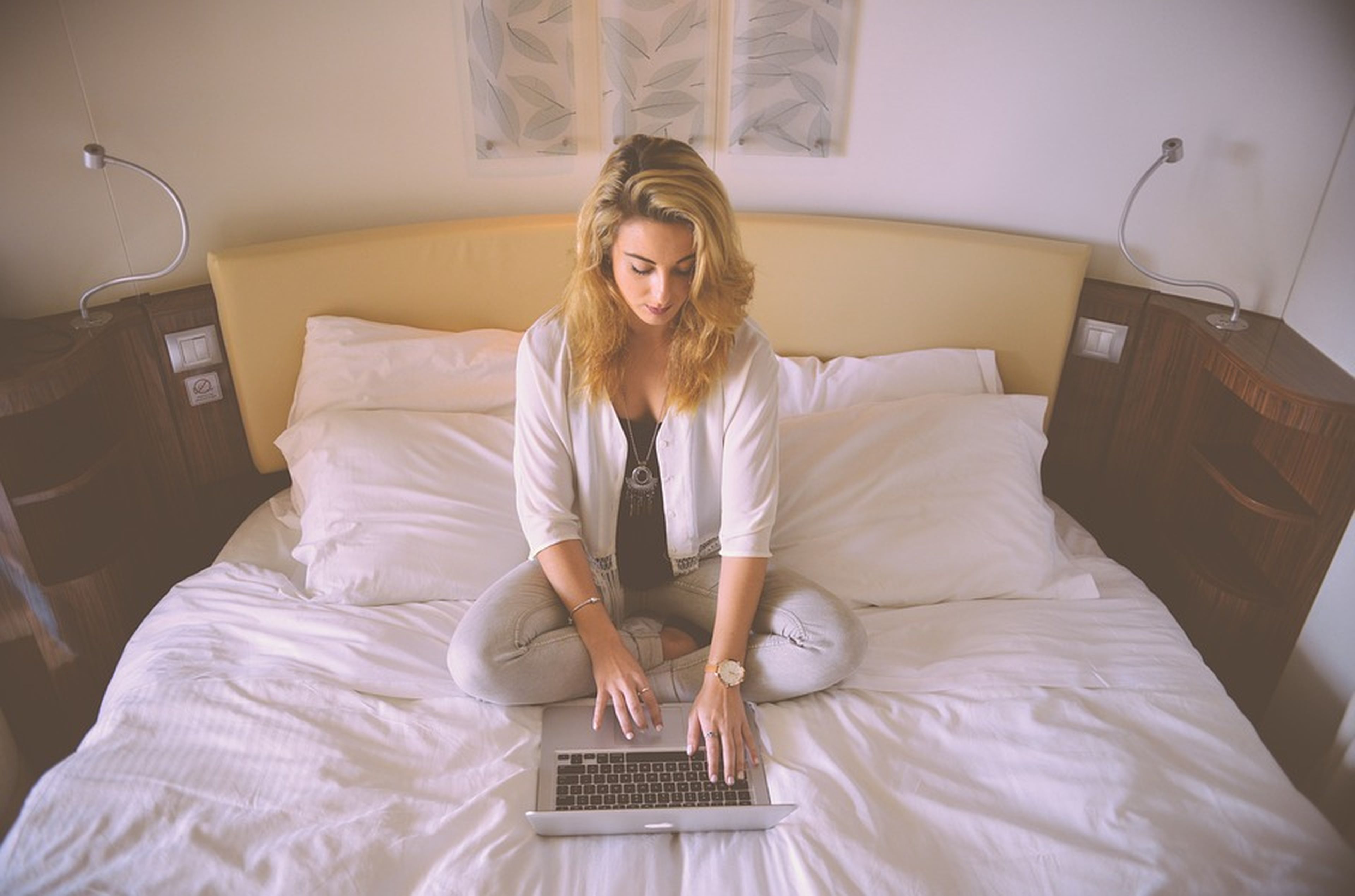 Mujer trabajando con su ordenador en la cama
