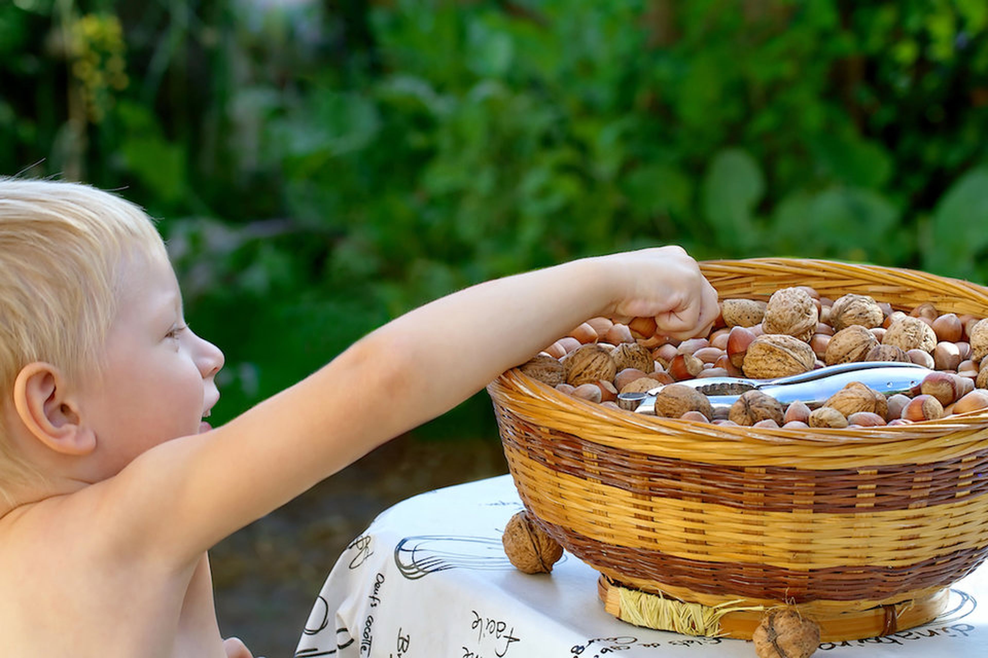 Un niño alcanza una cesta de nueces.