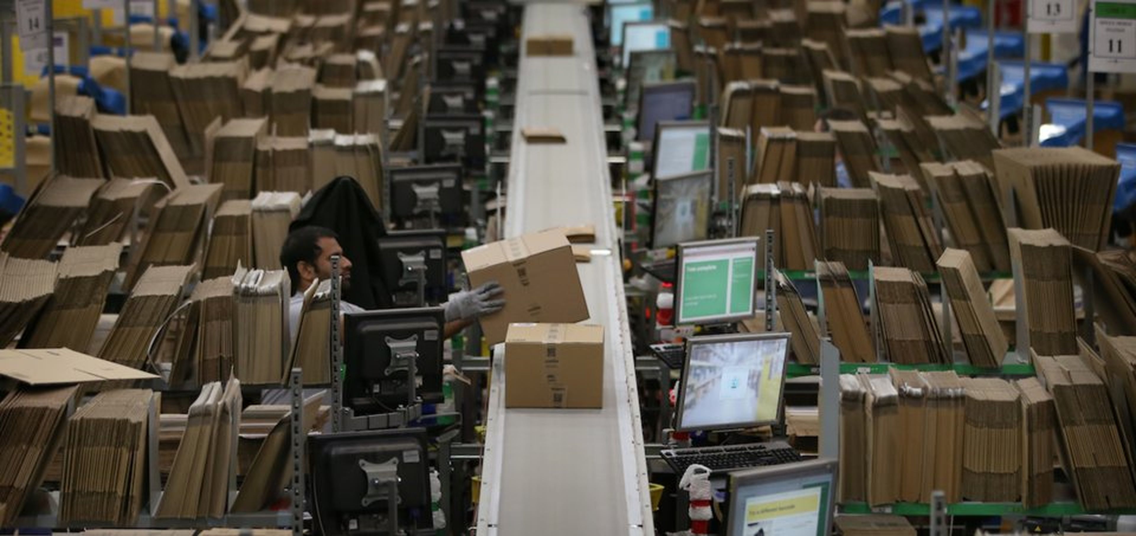 Un trabajador de Amazon coloca un paquete en una cinta