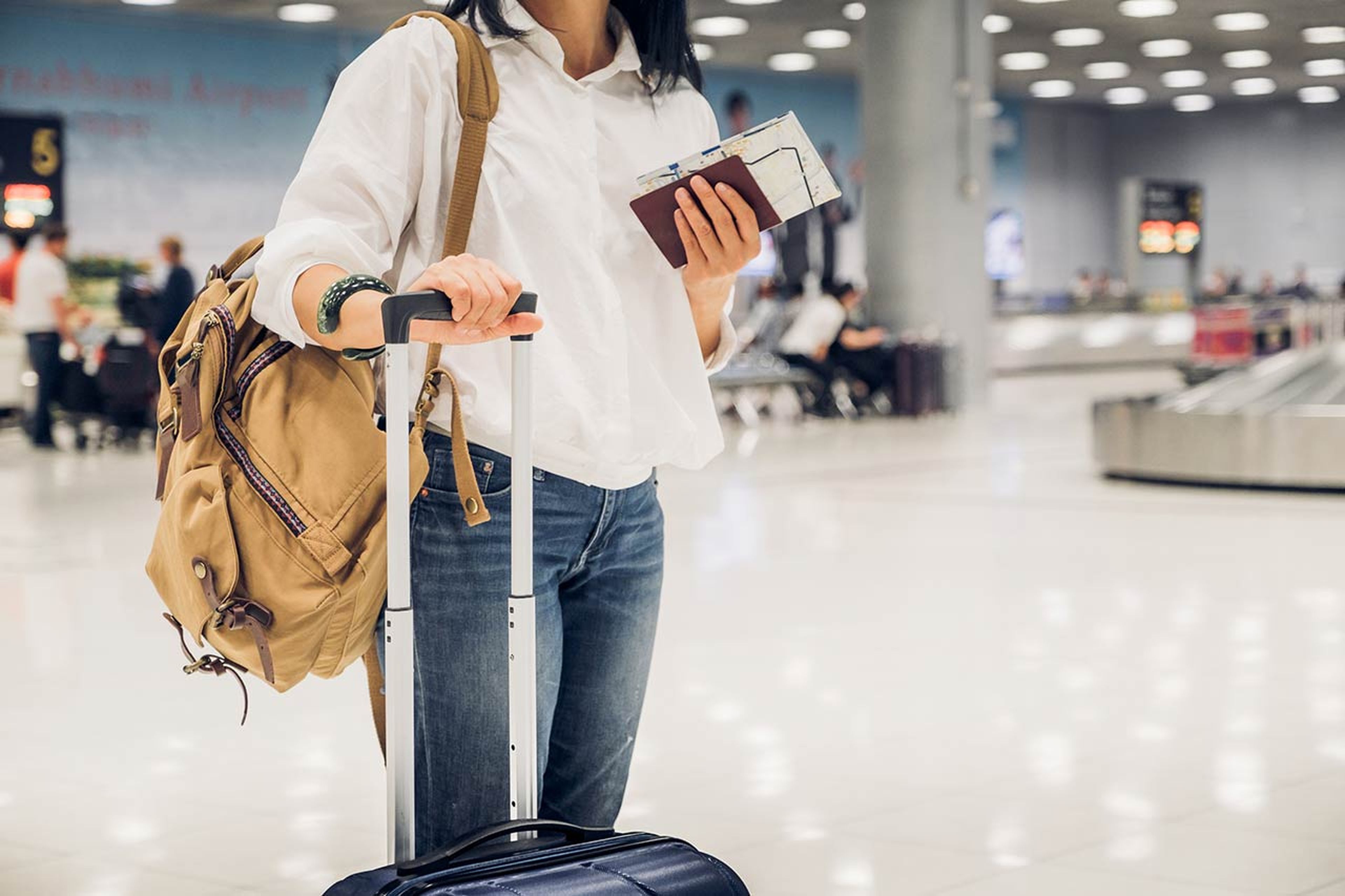 Chica con la maleta y el pasaporte en el aeropuerto