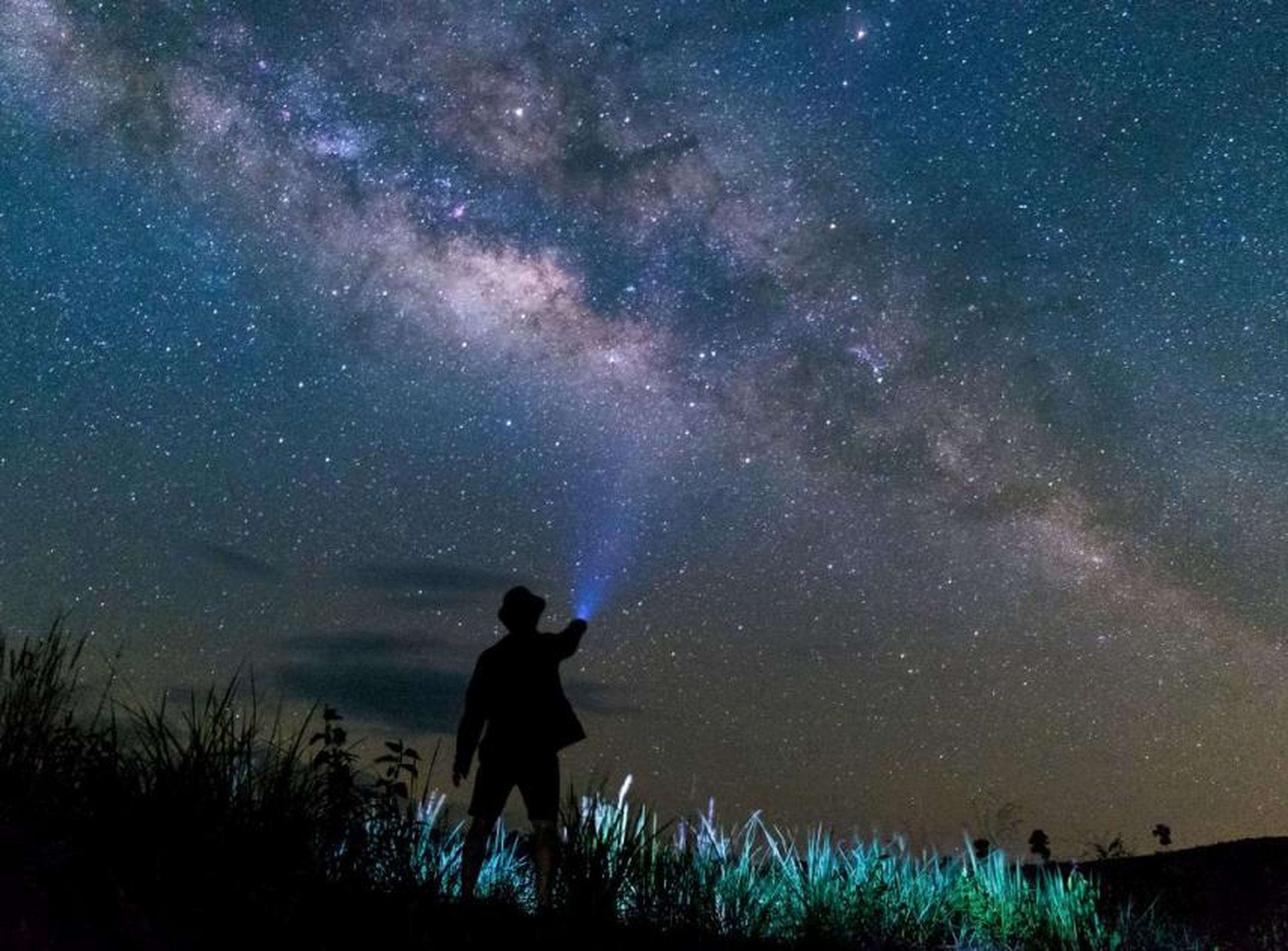Un hombre ilumina con su linterna el cielo estrellado