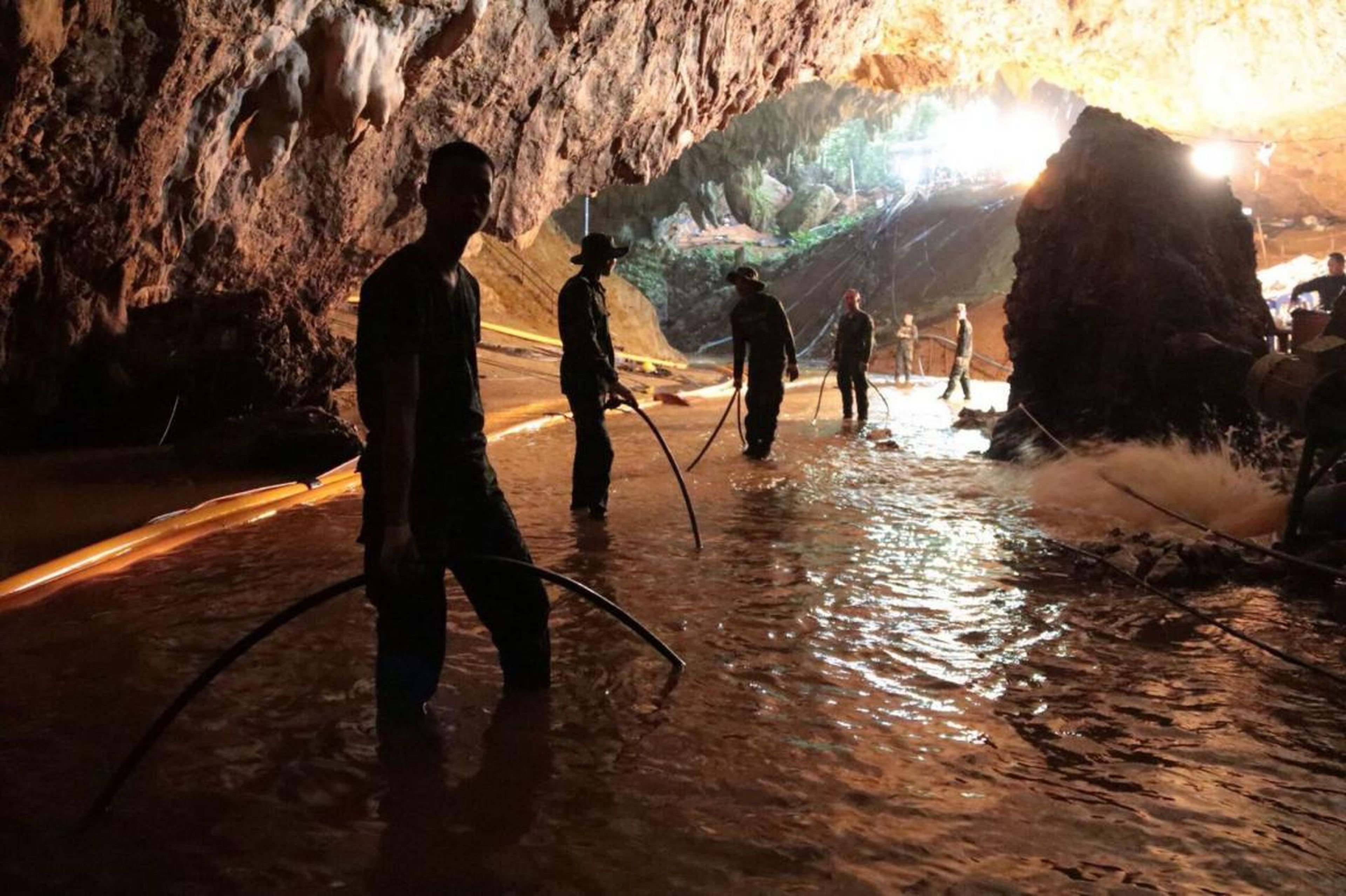 Thai rescue teams arrange a water pumping system at the entrance to a flooded cave complex where 12 boys and their soccer coach were trapped.