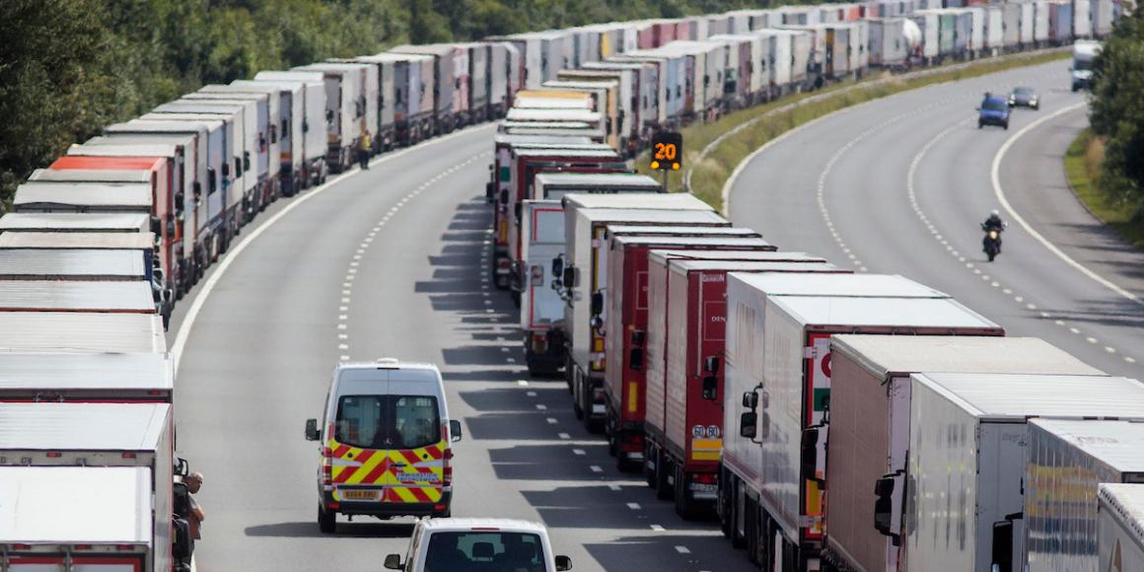 Immigration vehicles pass parked lorries on the M20 motorway, which leads from London to the Channel Tunnel terminal at Ashford and the Ferry Terminal at Dover, in southern England, Britain July 31, 2015.