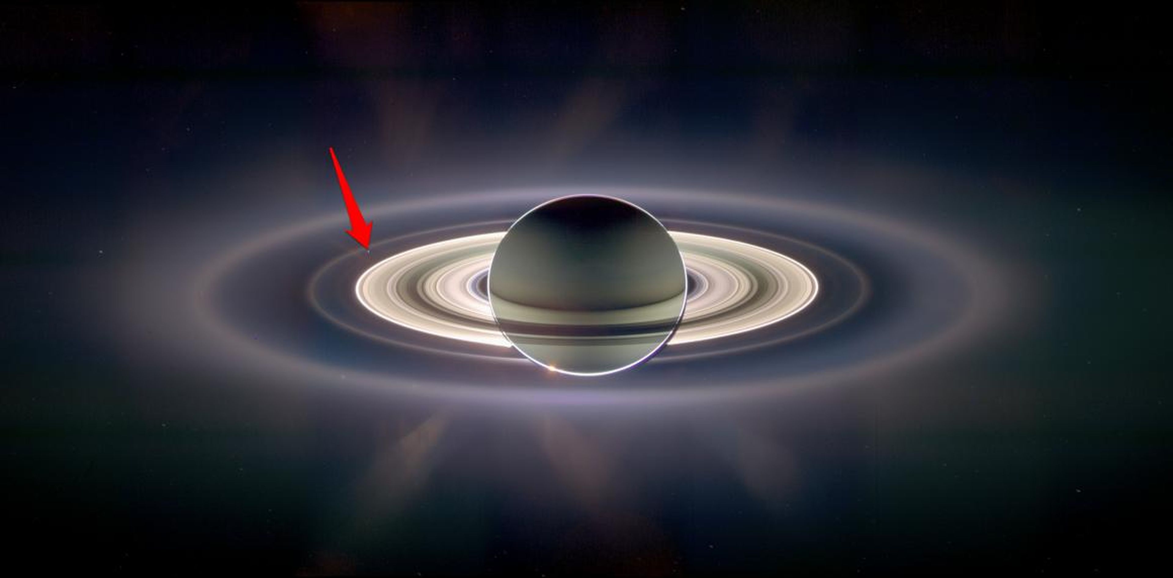 Vista desde Saturno, la Tierra parece desaparecer en el resplandor brillante de los anillos de hielo del gigante gaseoso