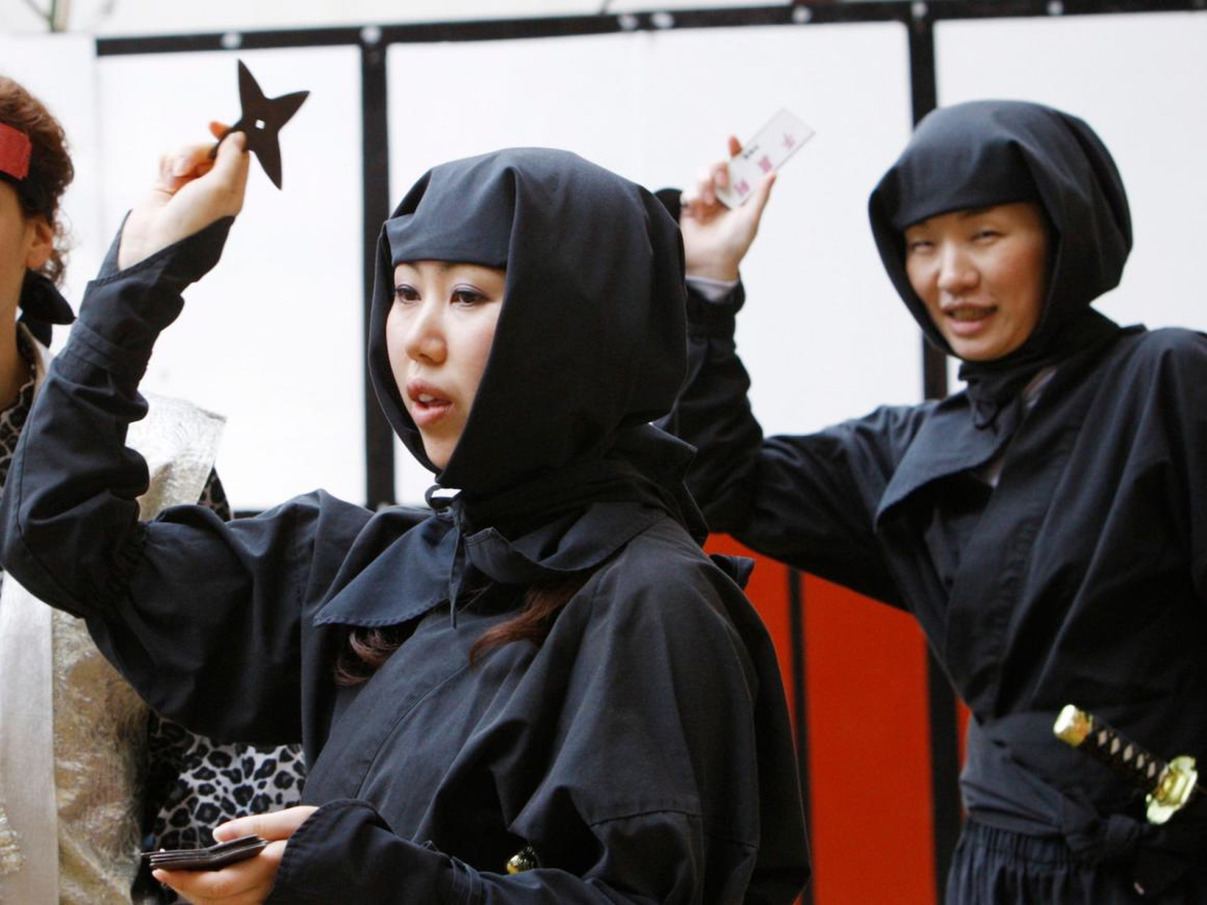 Women dressed as ninjas throwing "shuriken" during a ninja festival in Iga.