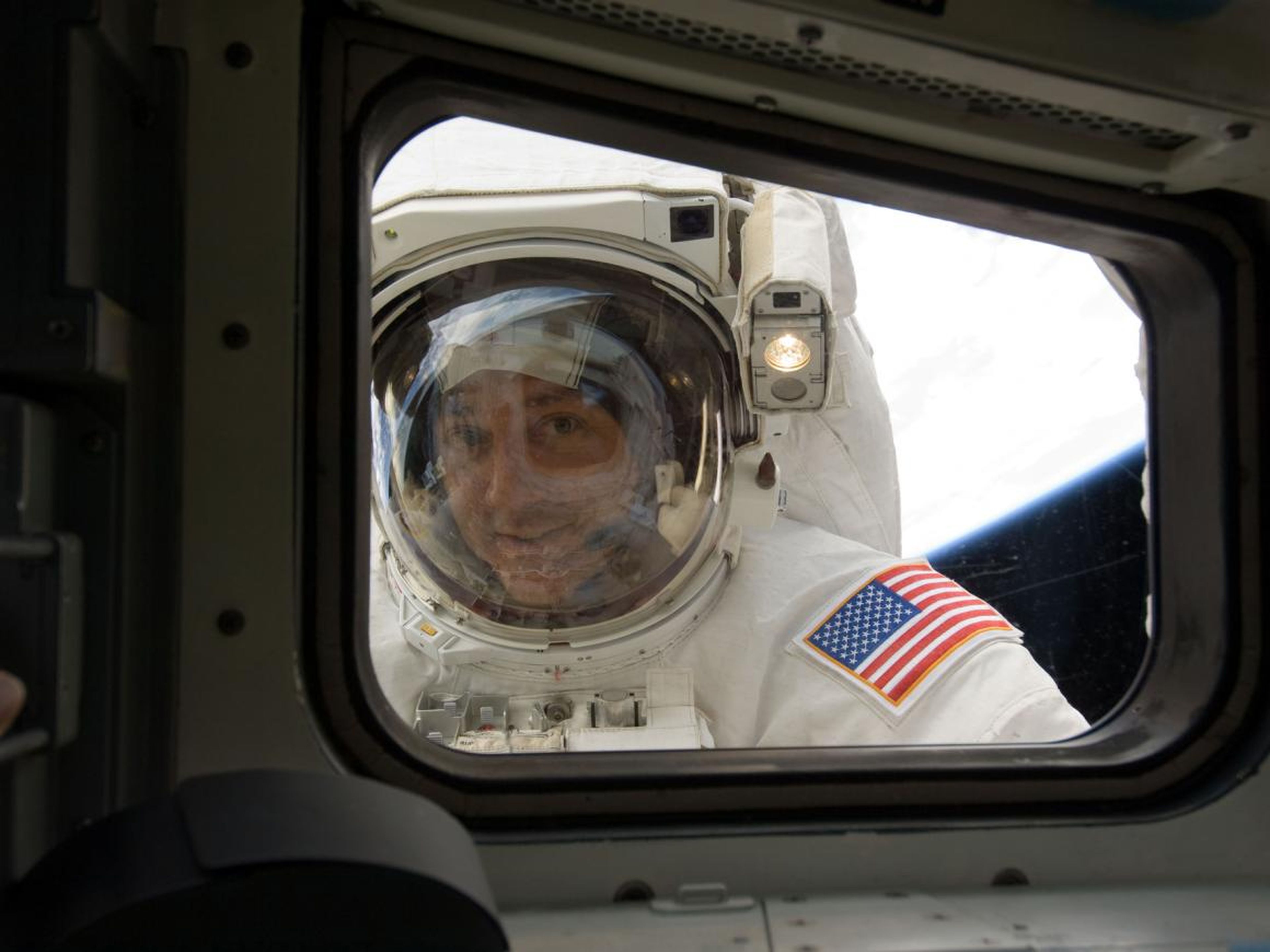 Massimino peers through the flight deck window while refurbishing and upgrading the Hubble Space Telescope in 2009.