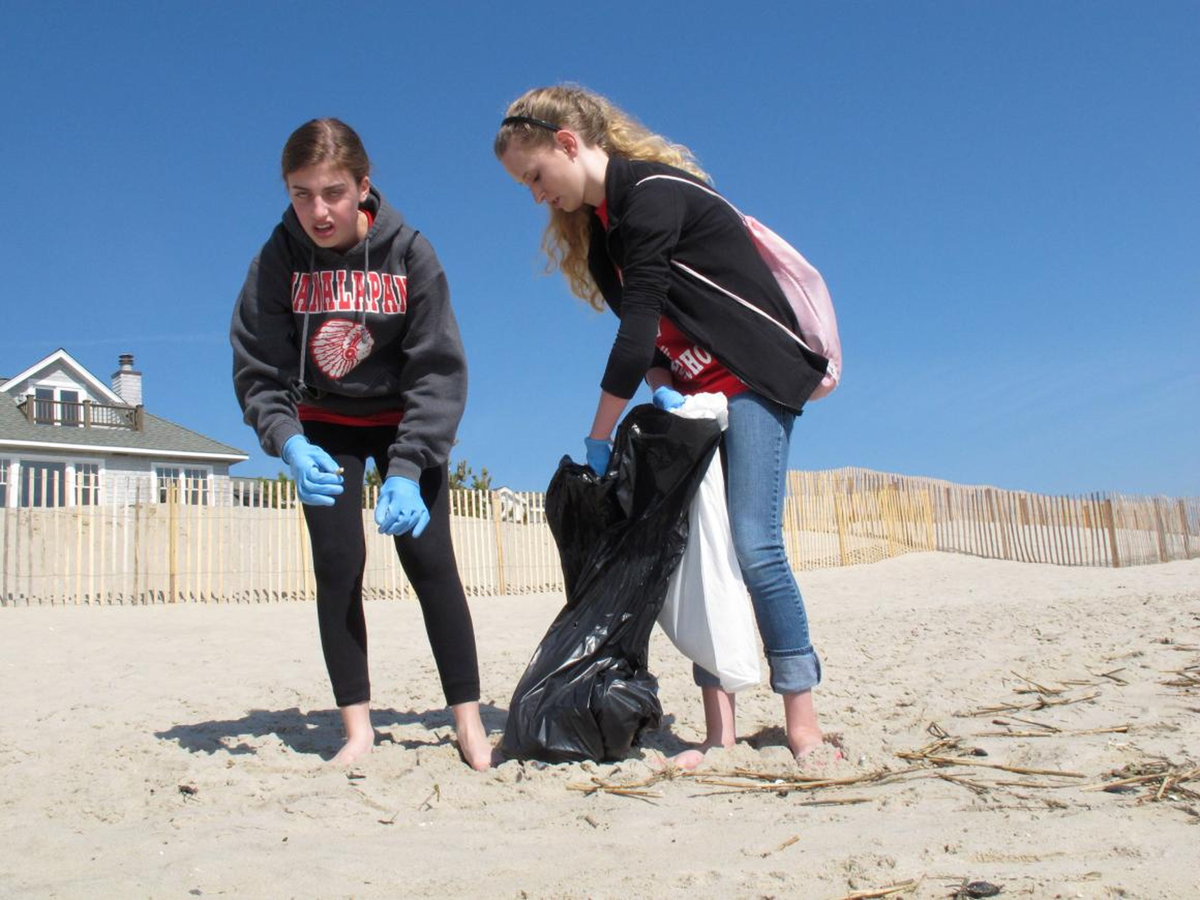 In an April 21, 2012 photo, Melissa Shapero reacts with disgust after picking up a cigarette butt from the beach in Point Pleasant Beach N.J. as Sarah Steward holds a trash bag for her.