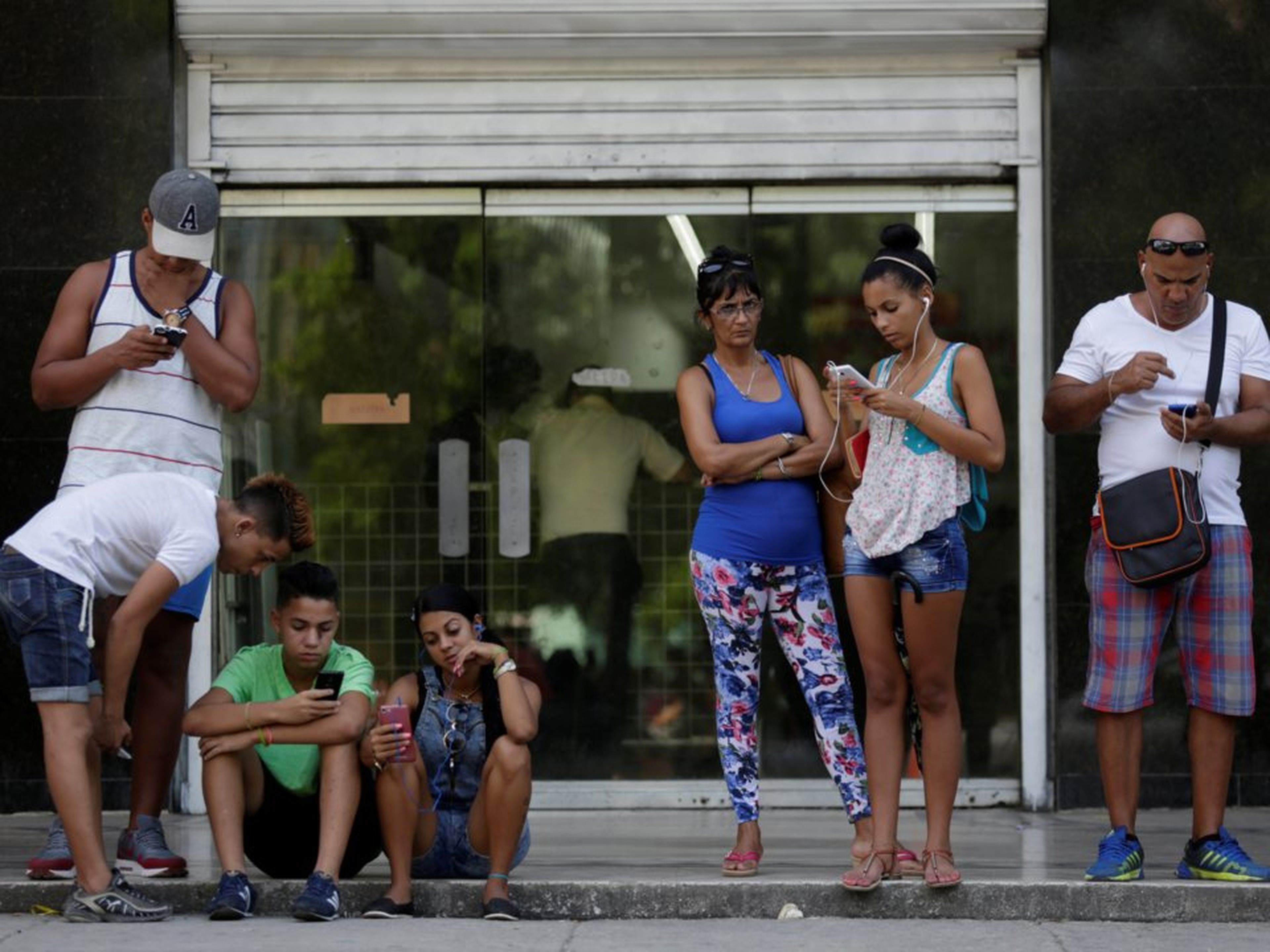 Cubanos conectándose a internet mediante Wi-Fi pública.