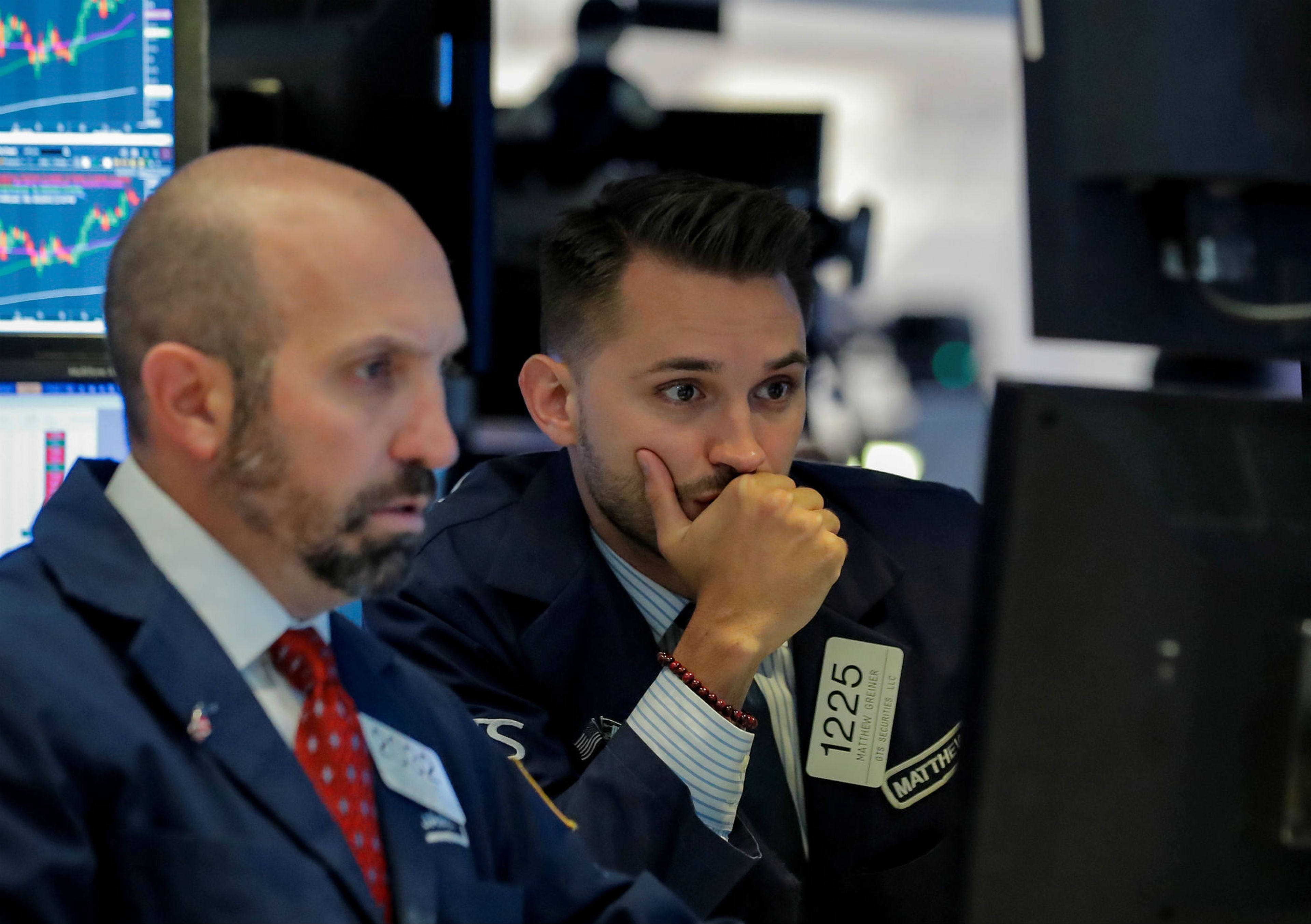 Dos traders en Wall Street mirando las pantallas de la cotización de la bolsa.