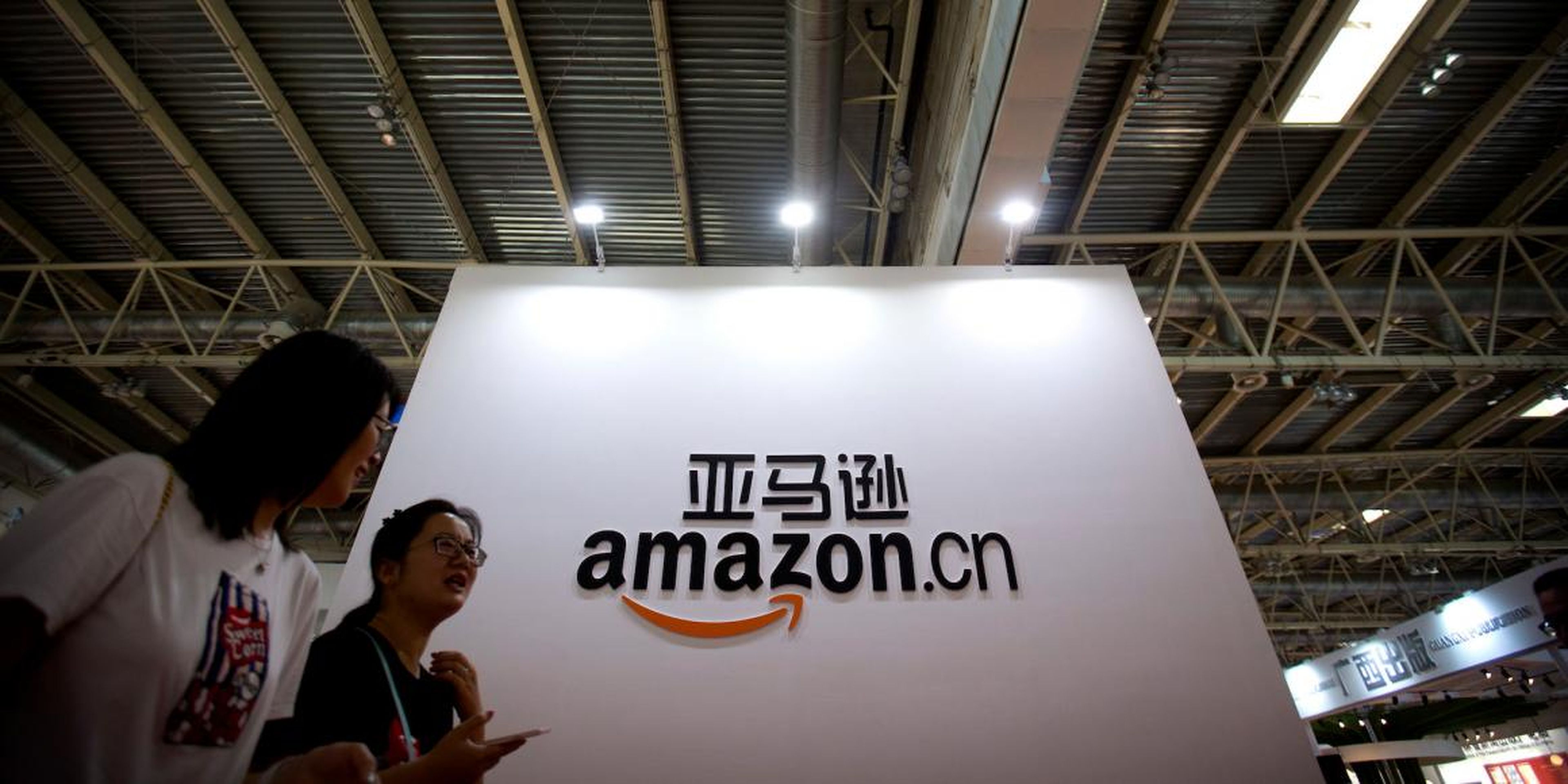 Los visitantes pasan junto a un logotipo de Amazon China en la Feria Internacional del Libro de Beijing en Beijing el 23 de agosto de 2017.
