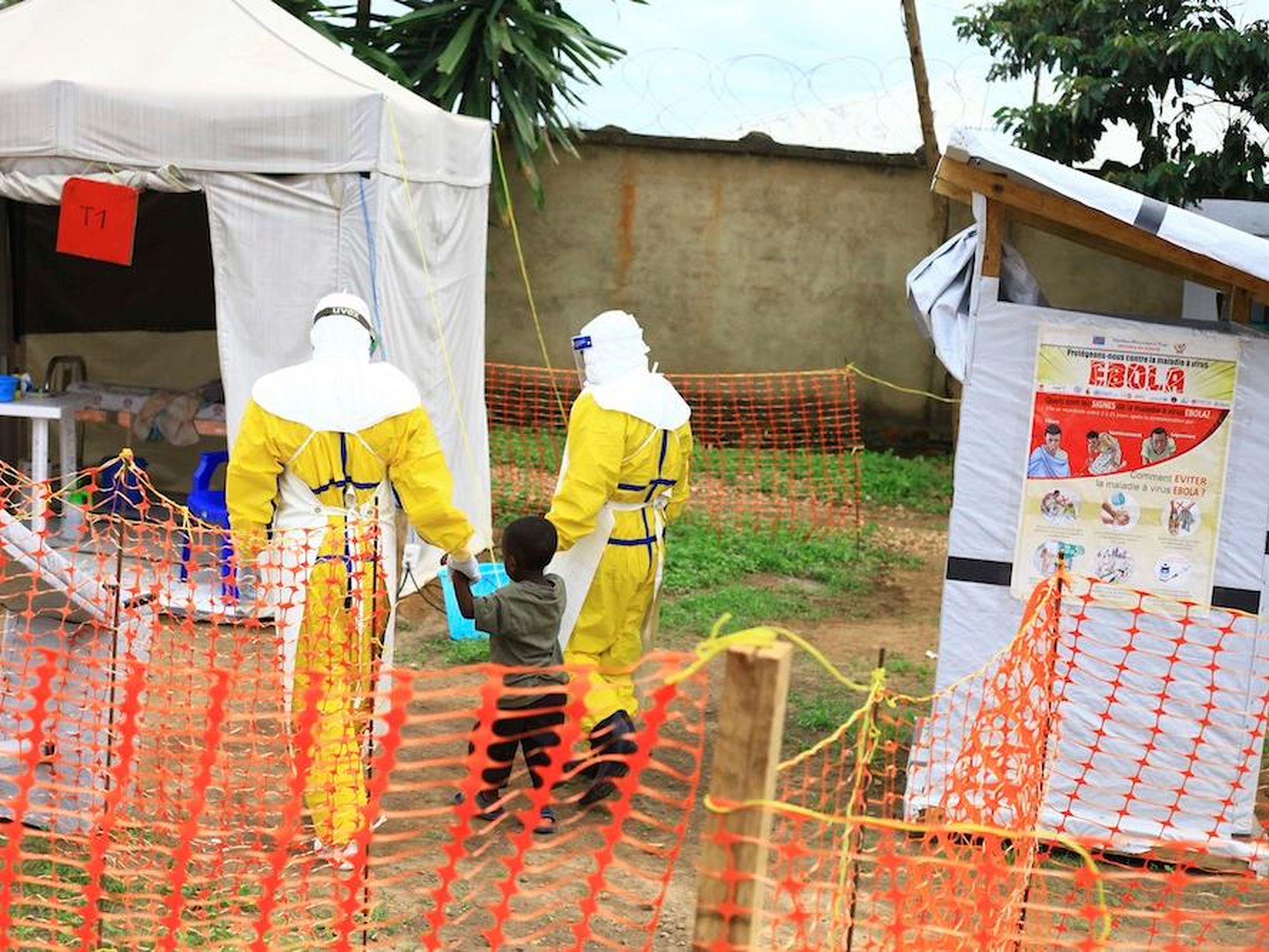 Profesionales de la salud caminan con un niño que se sospecha que está infectado con ébola en un centro de tratamiento en Beni, República Democrática del Congo.