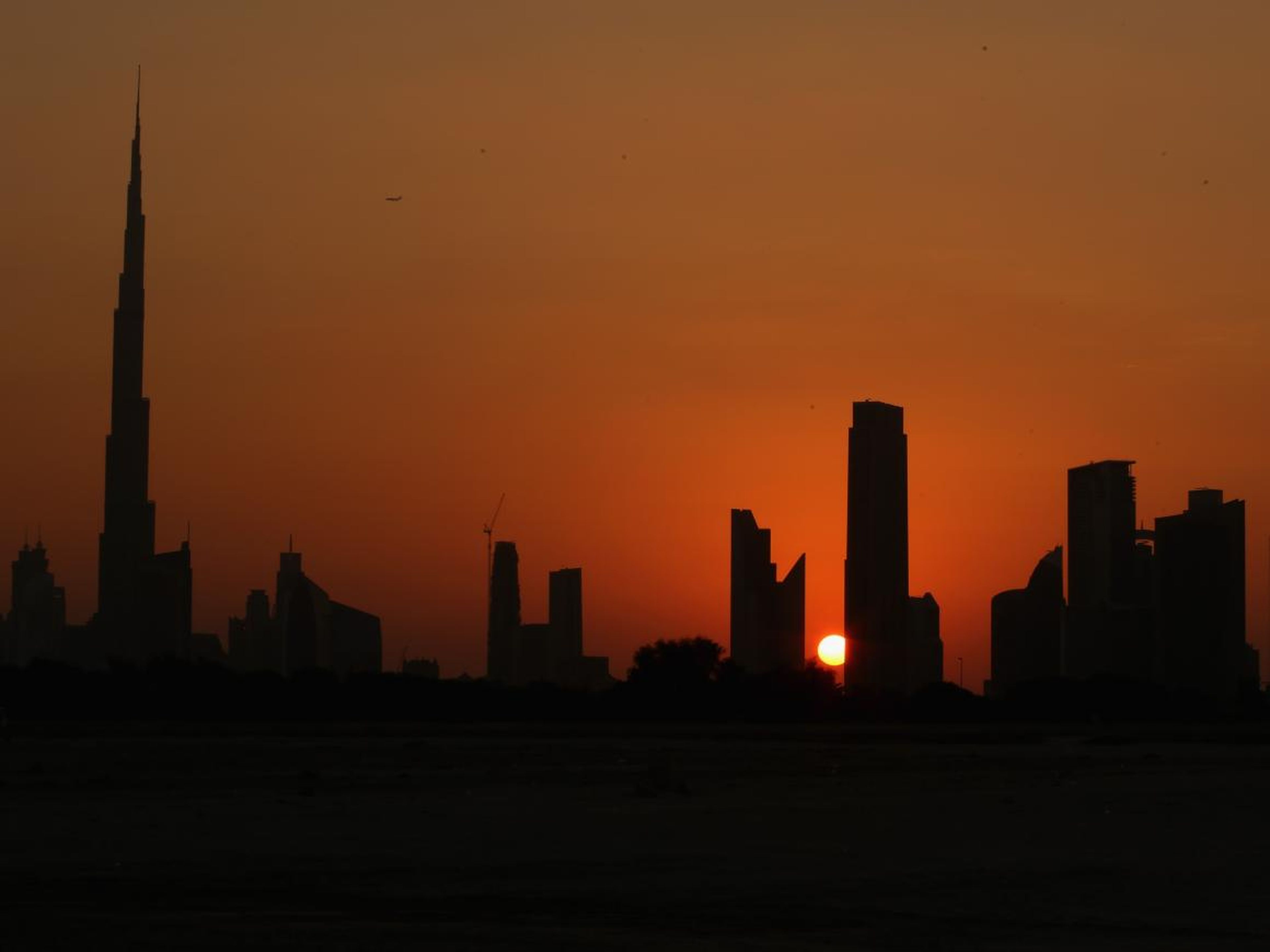 El sol se esconde tras el horizonte de Dubai, Emiratos Árabes Unidos.