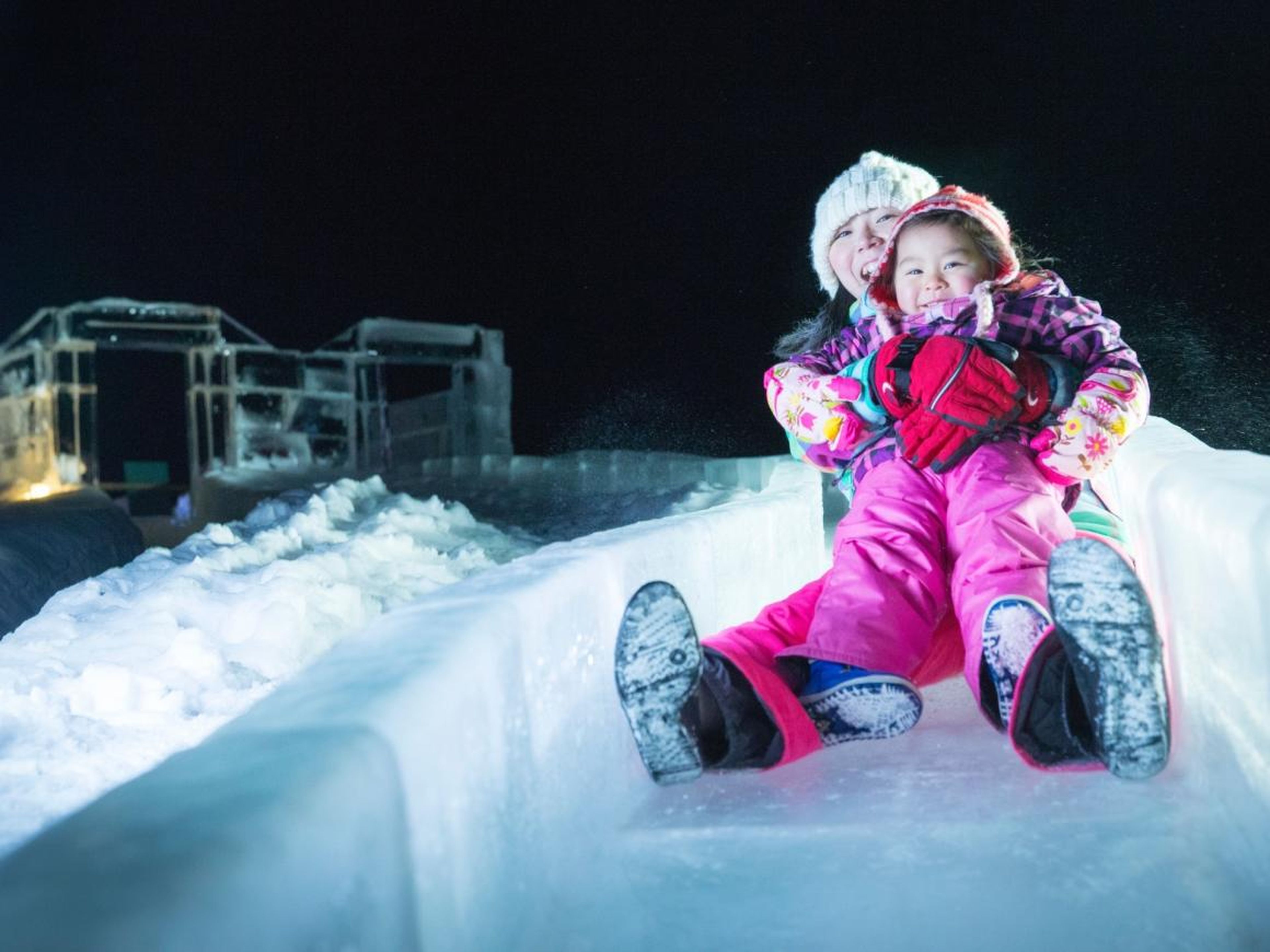 Una niña pequeña deslizándose por el tubo de hielo.
