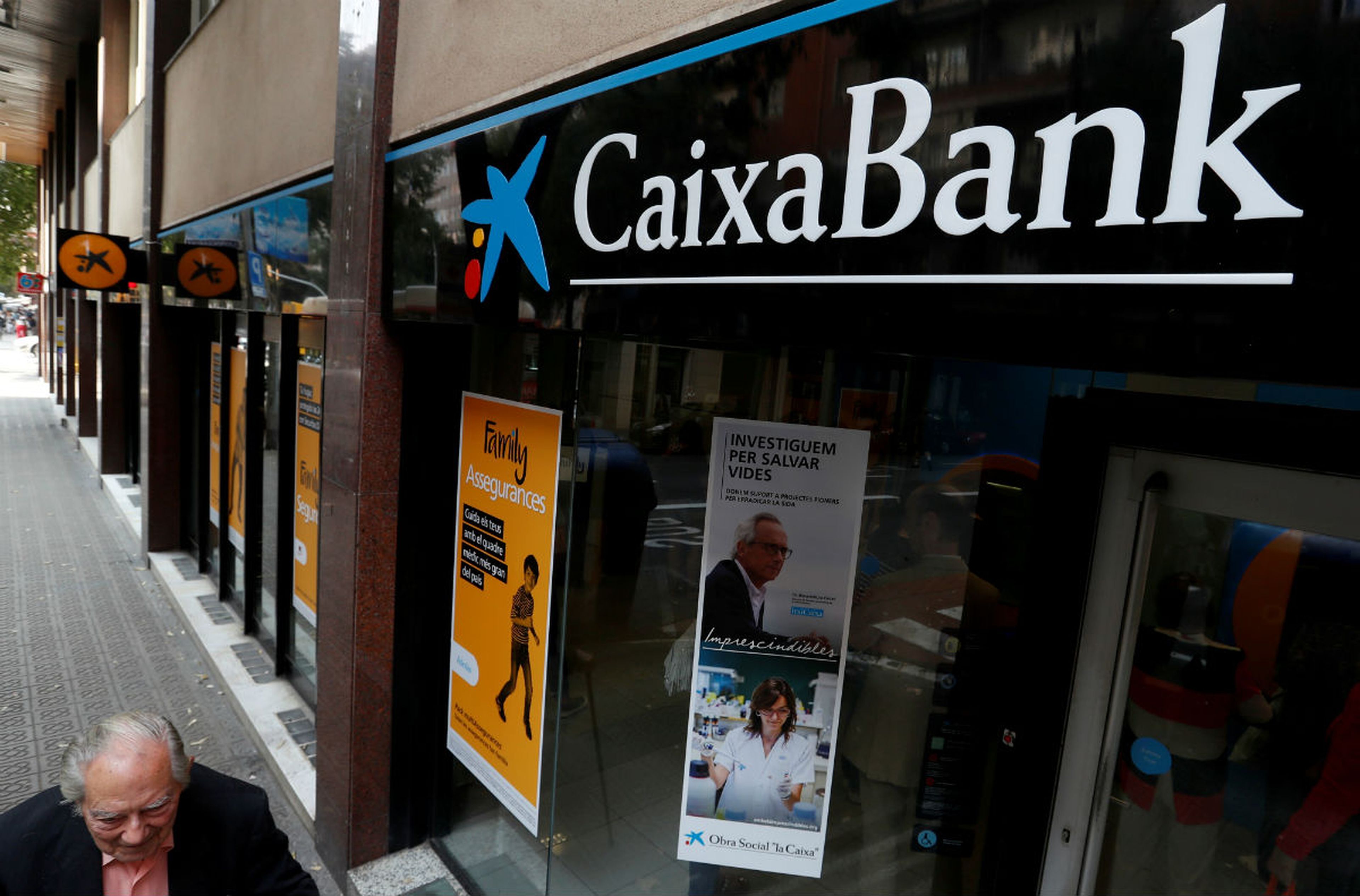 Un hombre pasa junto a una sucursal de CaixaBank en Barcelona