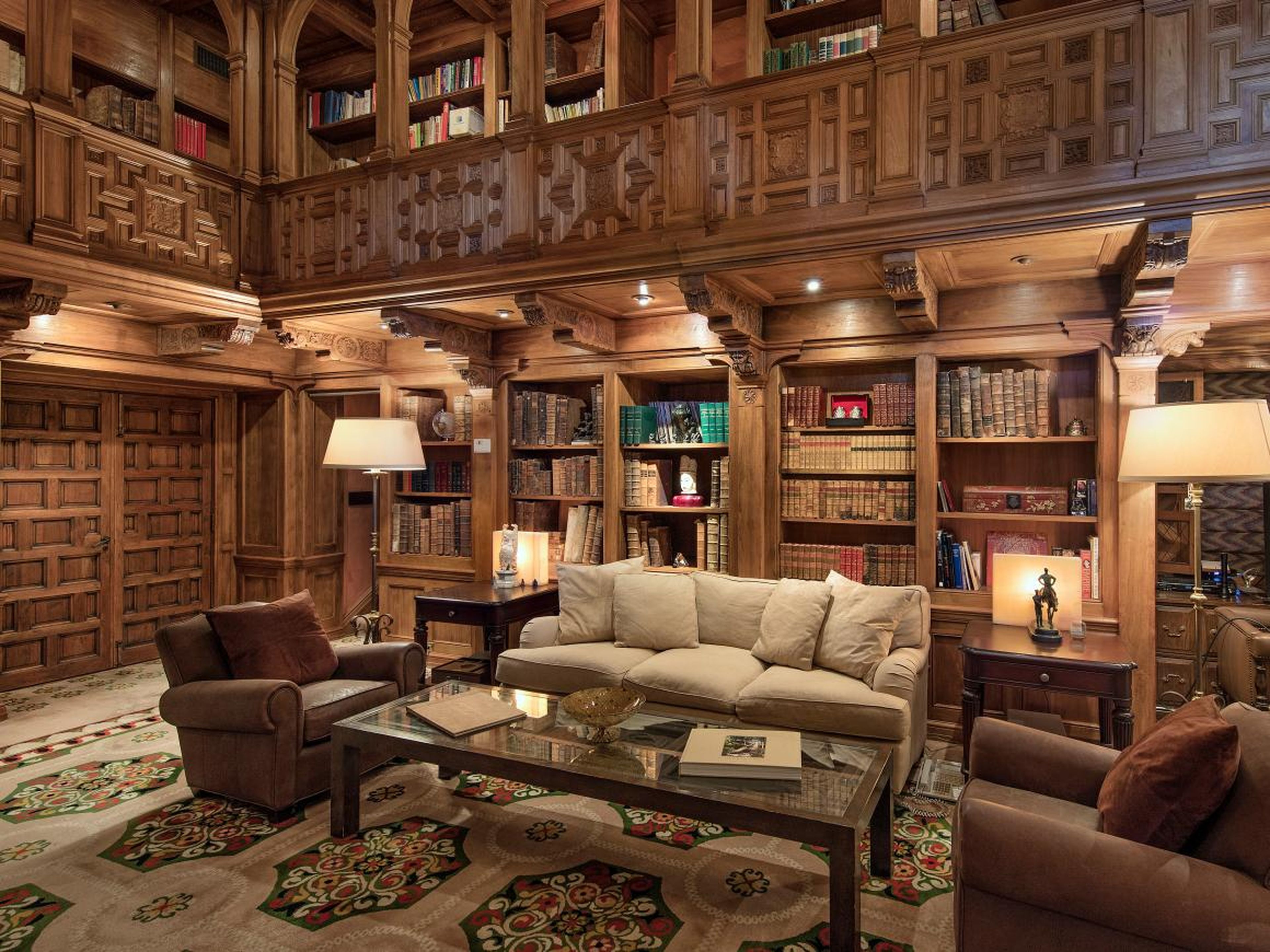 It includes an expansive, two-story library with hand-carved paneling and a detailed ceiling.