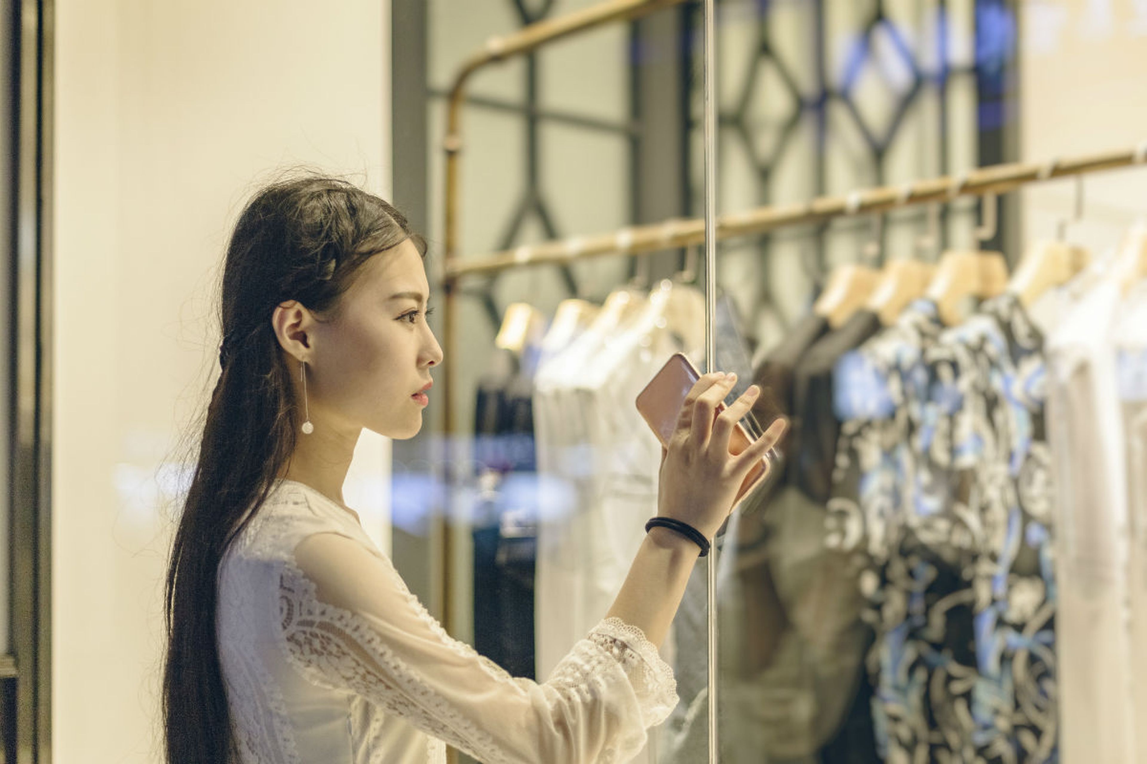 Una mujer observa el escaparate de una tienda de moda en Pekín