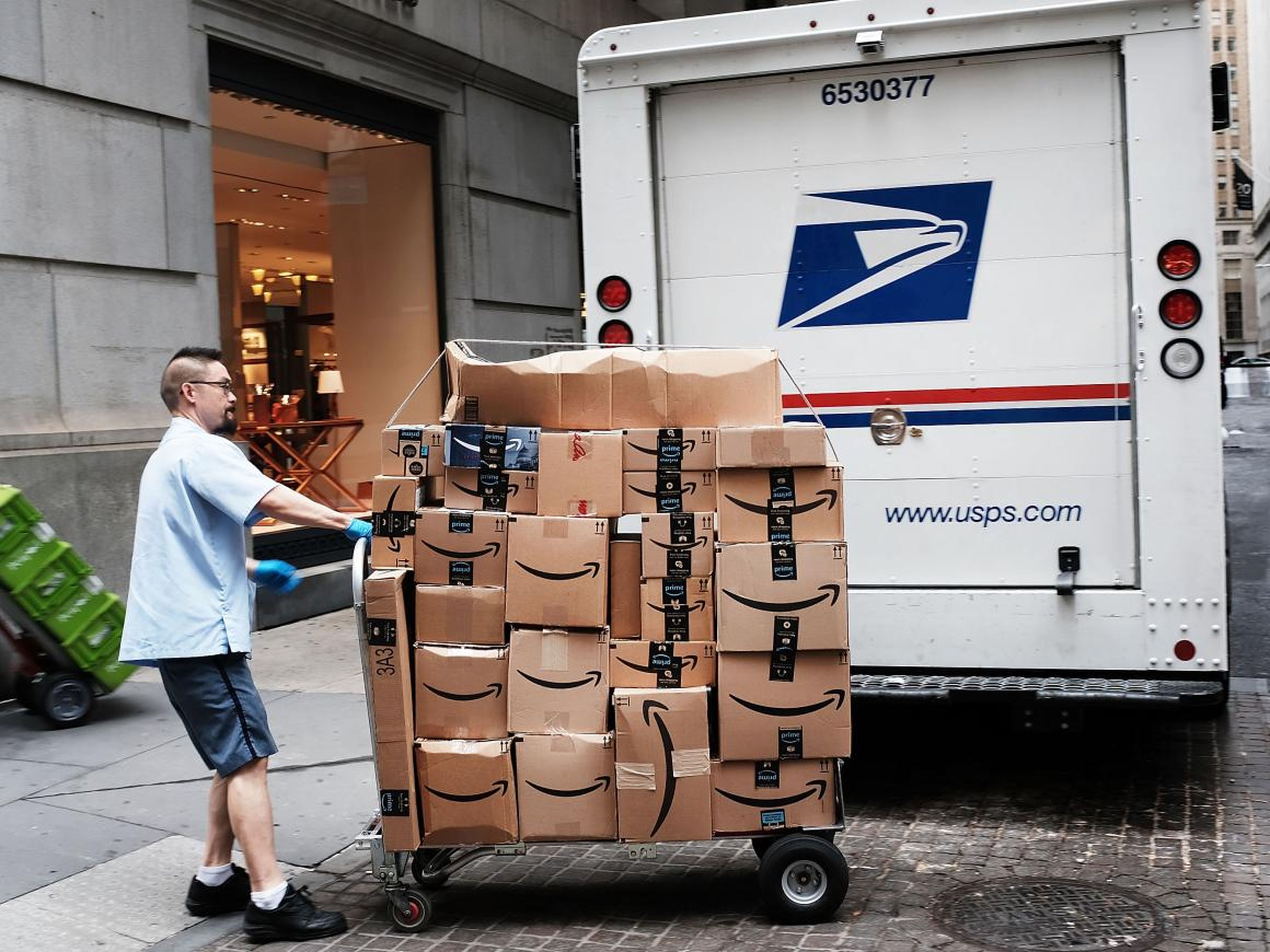 A USPS worker delivering Amazon packages to businesses.