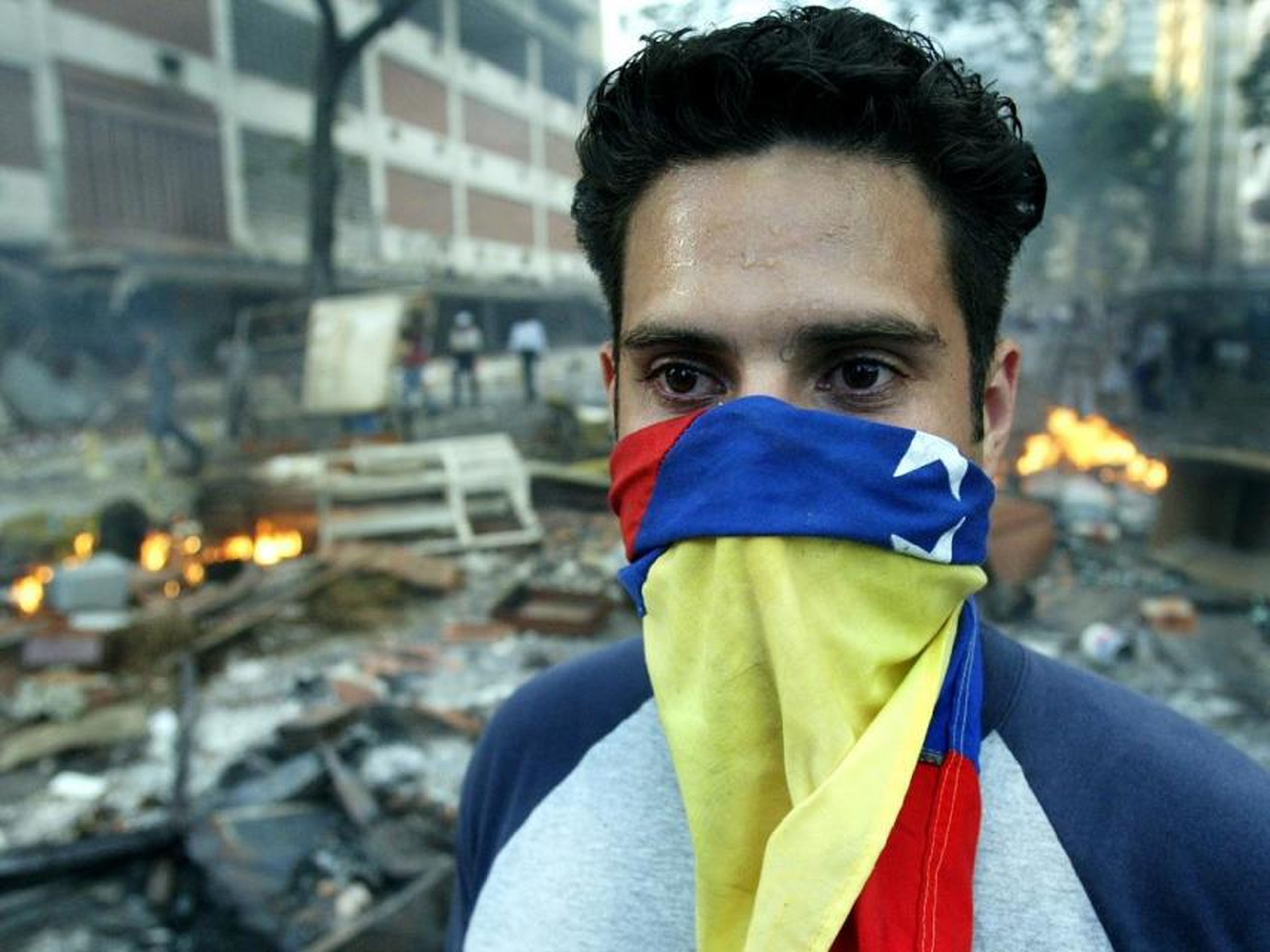 Un manifestante venezolano enmascarado se para frente a una barricada en llamas durante los disturbios en Caracas, el 1 de marzo de 2004.