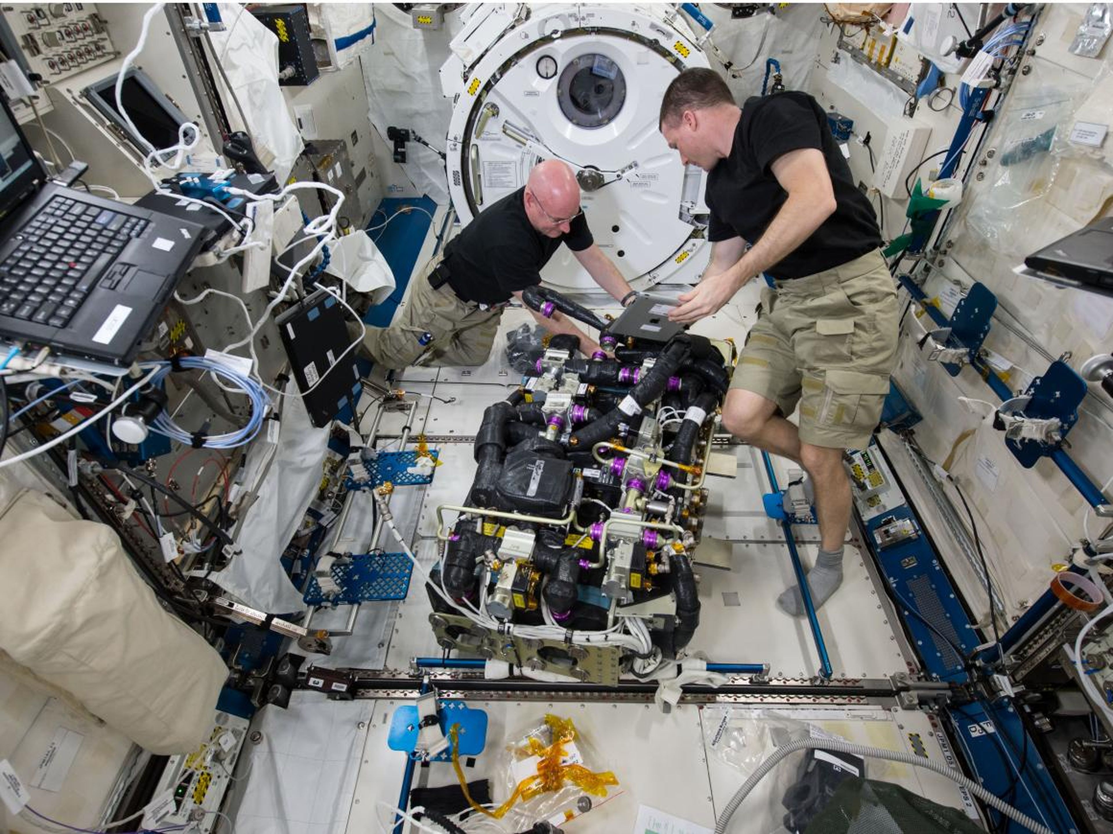 NASA astronauts Scott Kelly (left) and Terry Virts (right) work on a Carbon Dioxide Removal Assembly inside the station's Japanese Experiment Module.