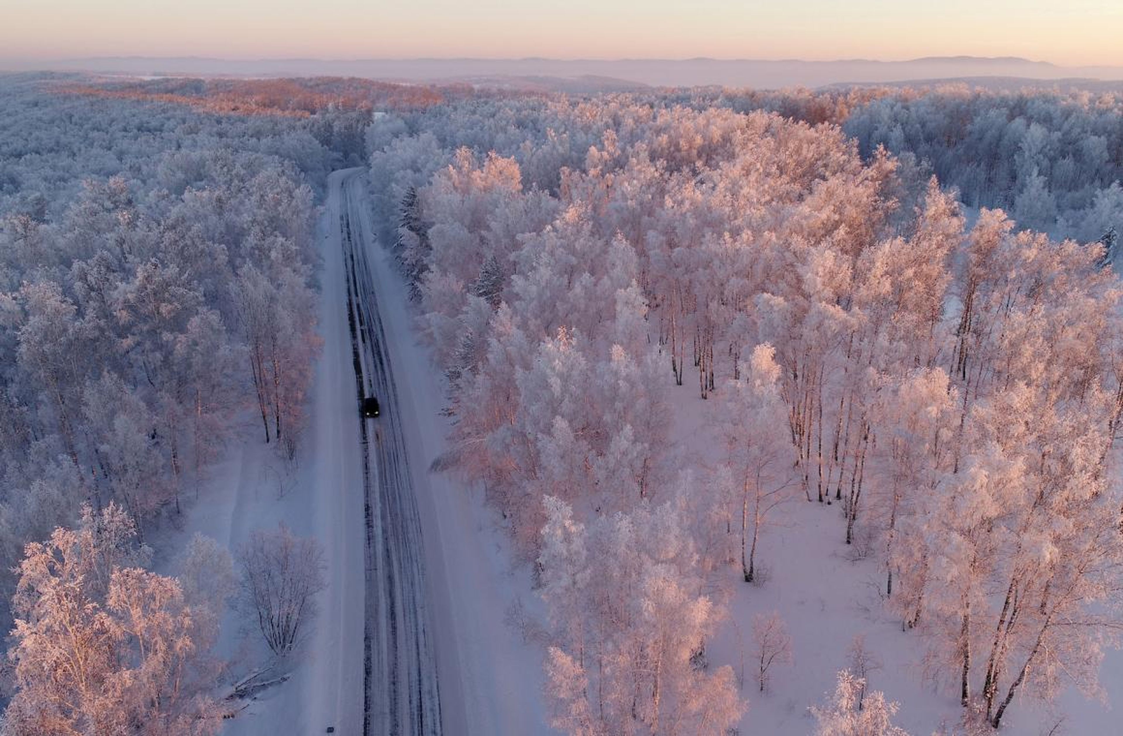 A car drives along a forest road in the Krasnoyarsk region, Russia.