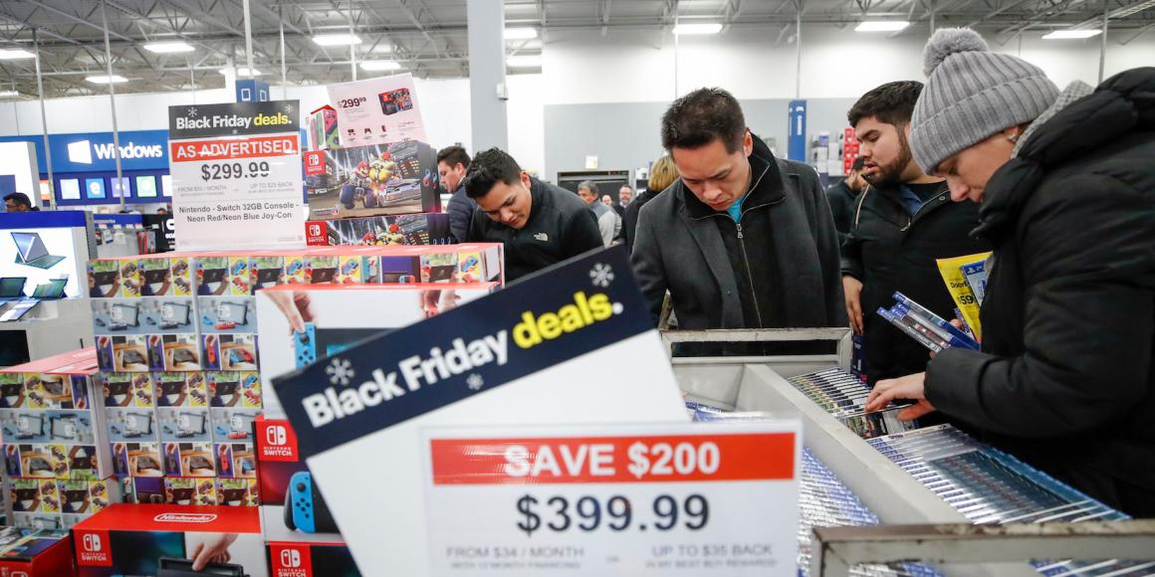 Compradores en una tienda Best Buy buscando ofertas de Black Friday.