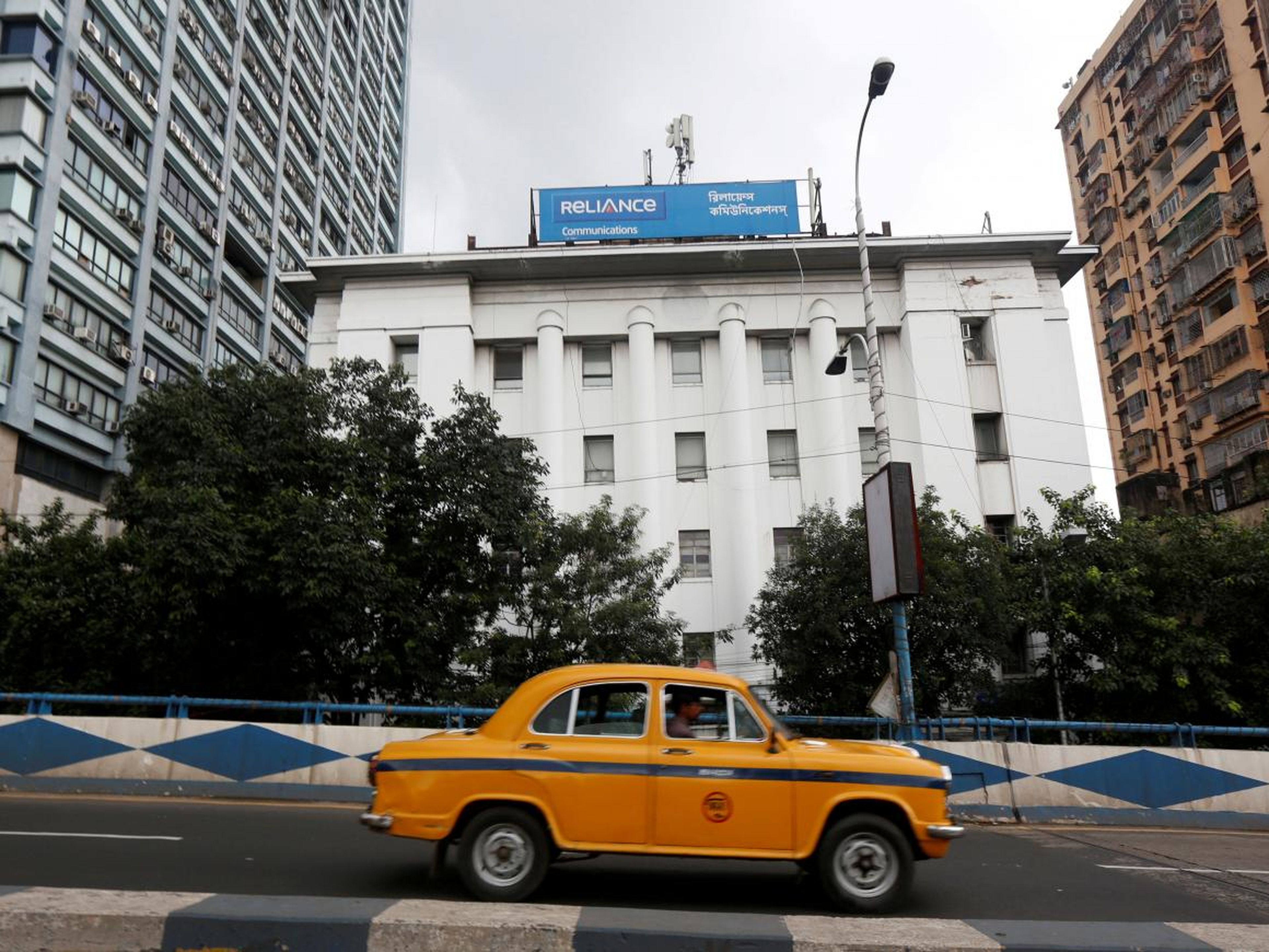 A taxi drives past a Reliance Communications building in Kolkata, India.