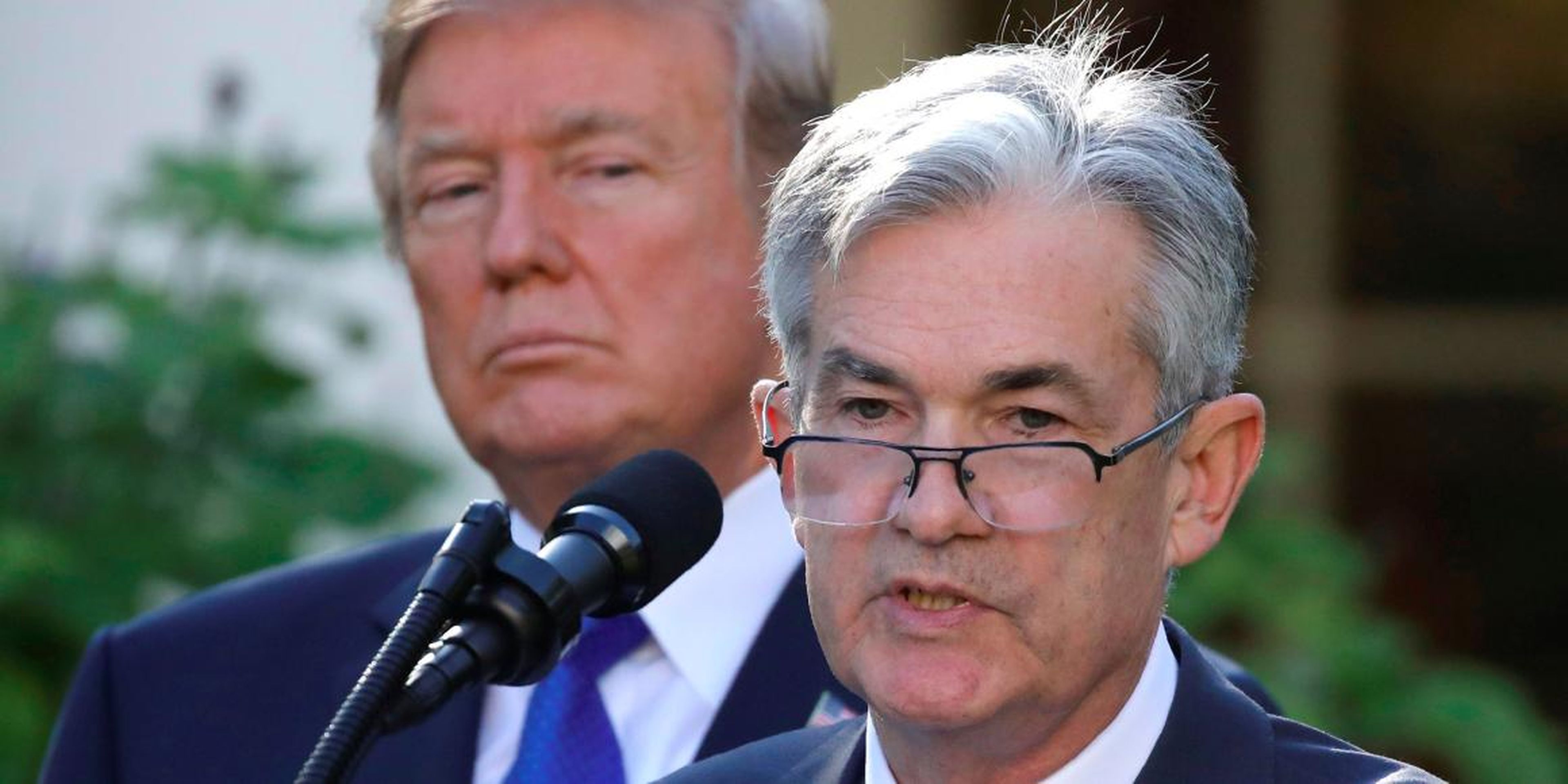 President Donald Trump stands behind Federal Reserve chairman Jerome Powell.