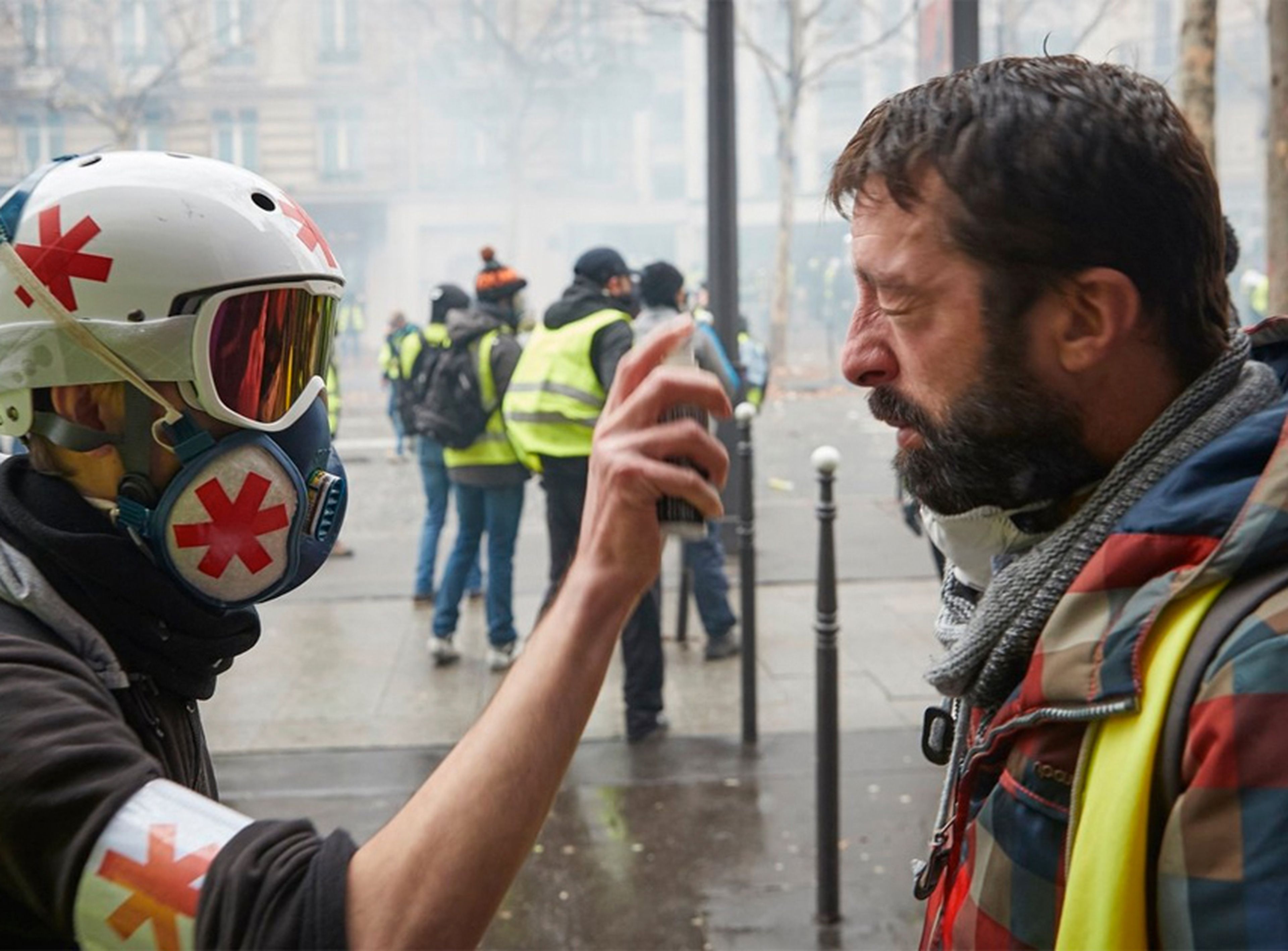 Un médico voluntario ayuda a un manifestante que sufre los efectos de los gases lacrimógenos disparado por la policía francesa, en el tercer acto de la protesta de los 'Gilets Jaunes' en París, este sábado 1 de diciembre.