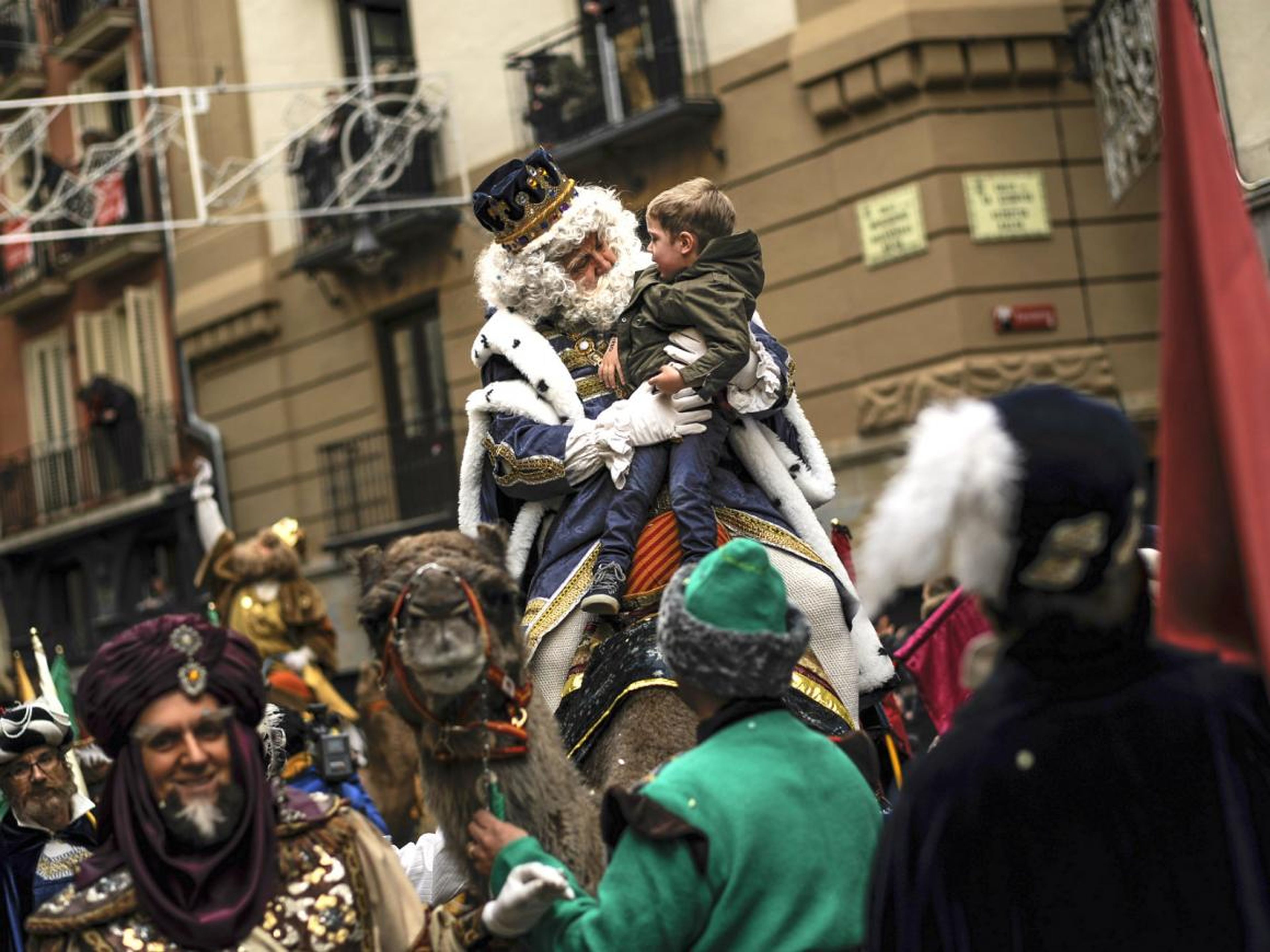 One of the Reyes Magos holds a young boy on his lap during a celebration in Pamplona, Spain.