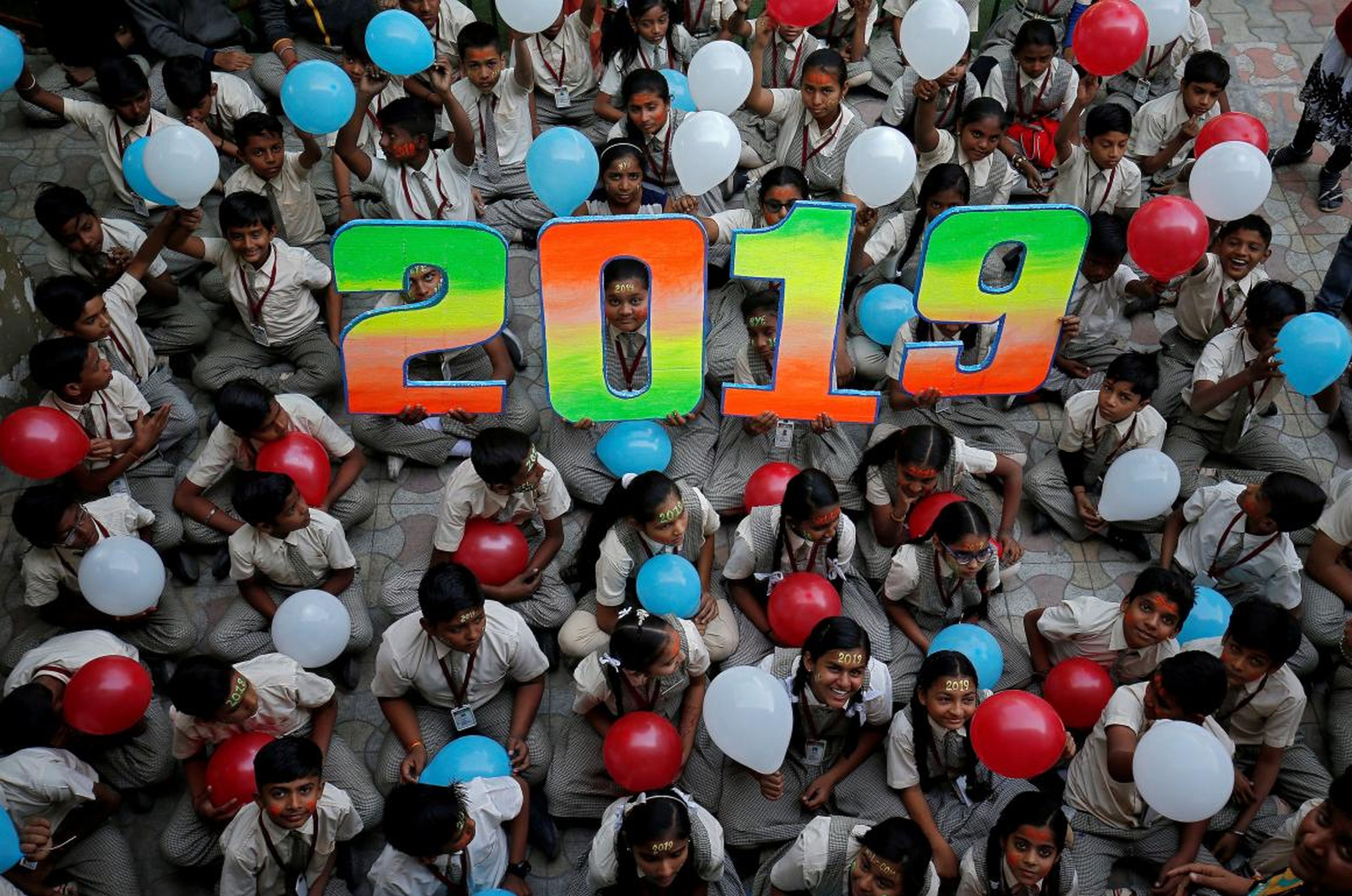 Un grupo de niños sostiene globos mientras posan durante las celebraciones para dar la bienvenida al Año Nuevo en su escuela de Ahmedabad, India, el 31 de diciembre de 2018.