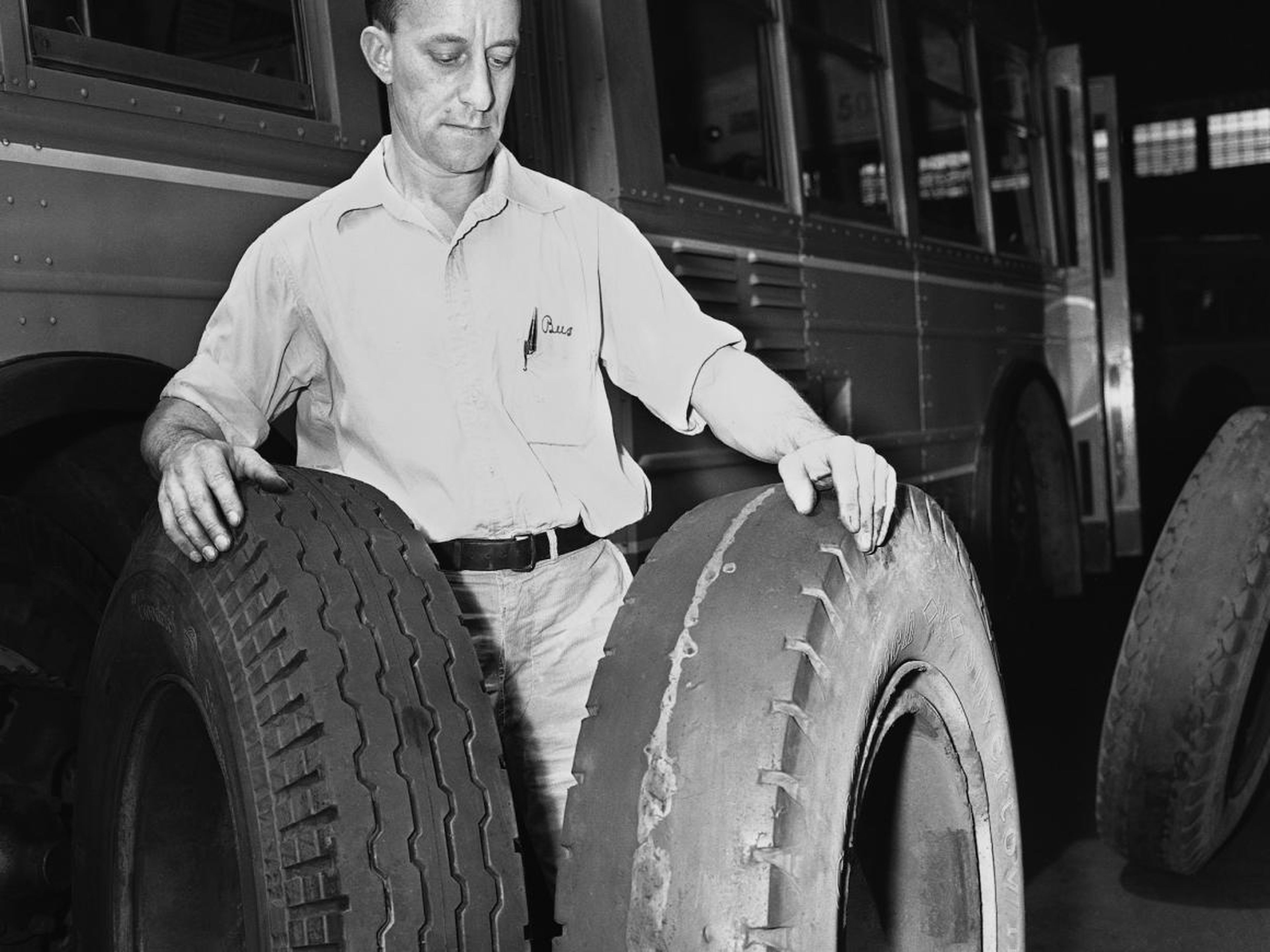 A tire service manager in the US in 1942 compares a tire made of synthetic rubber (left) with one made of latex.