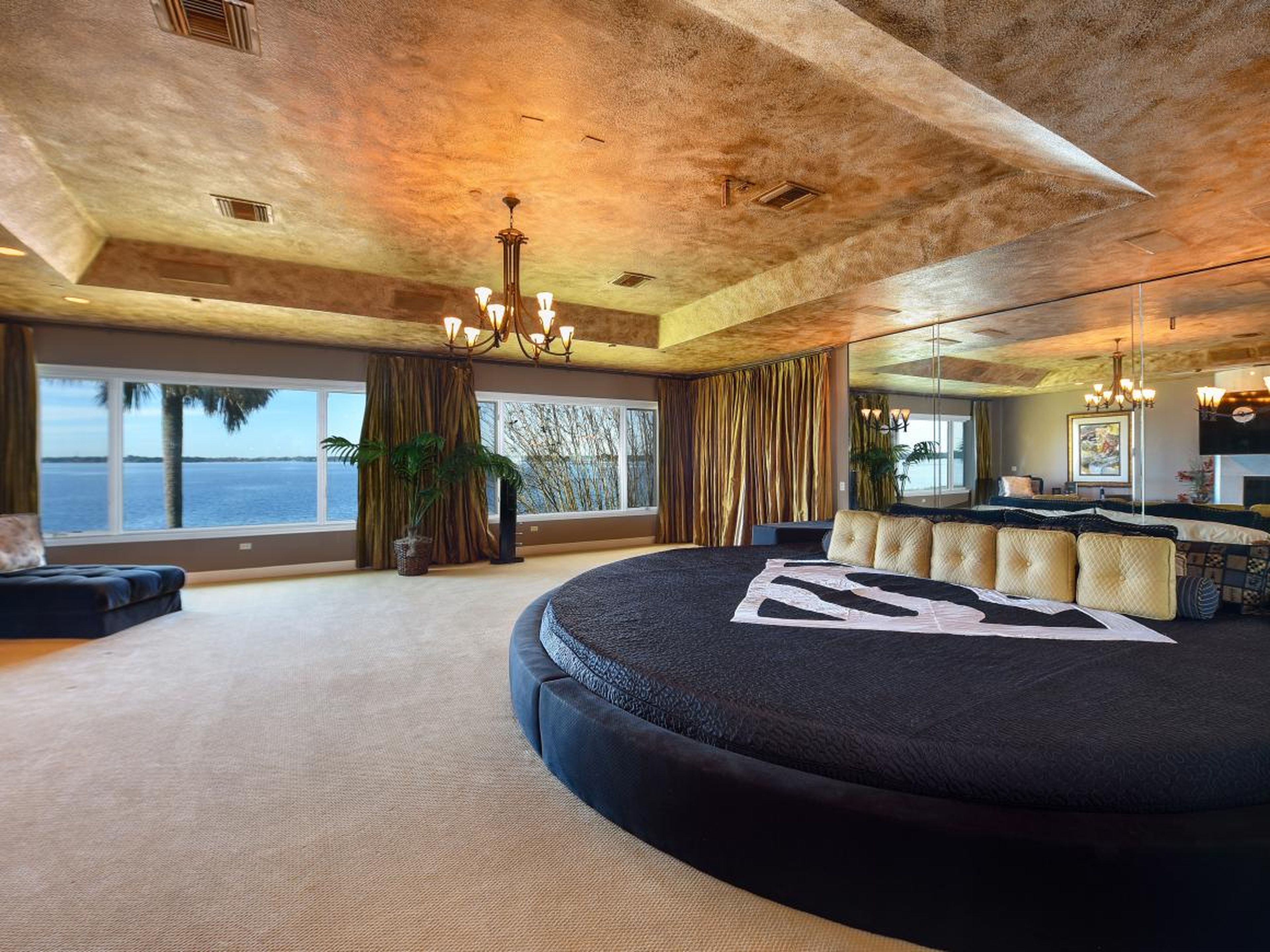 The master suite has a spacious walk-in closet, a mirrored wall, a gilded ceiling, and expansive views of the lake.